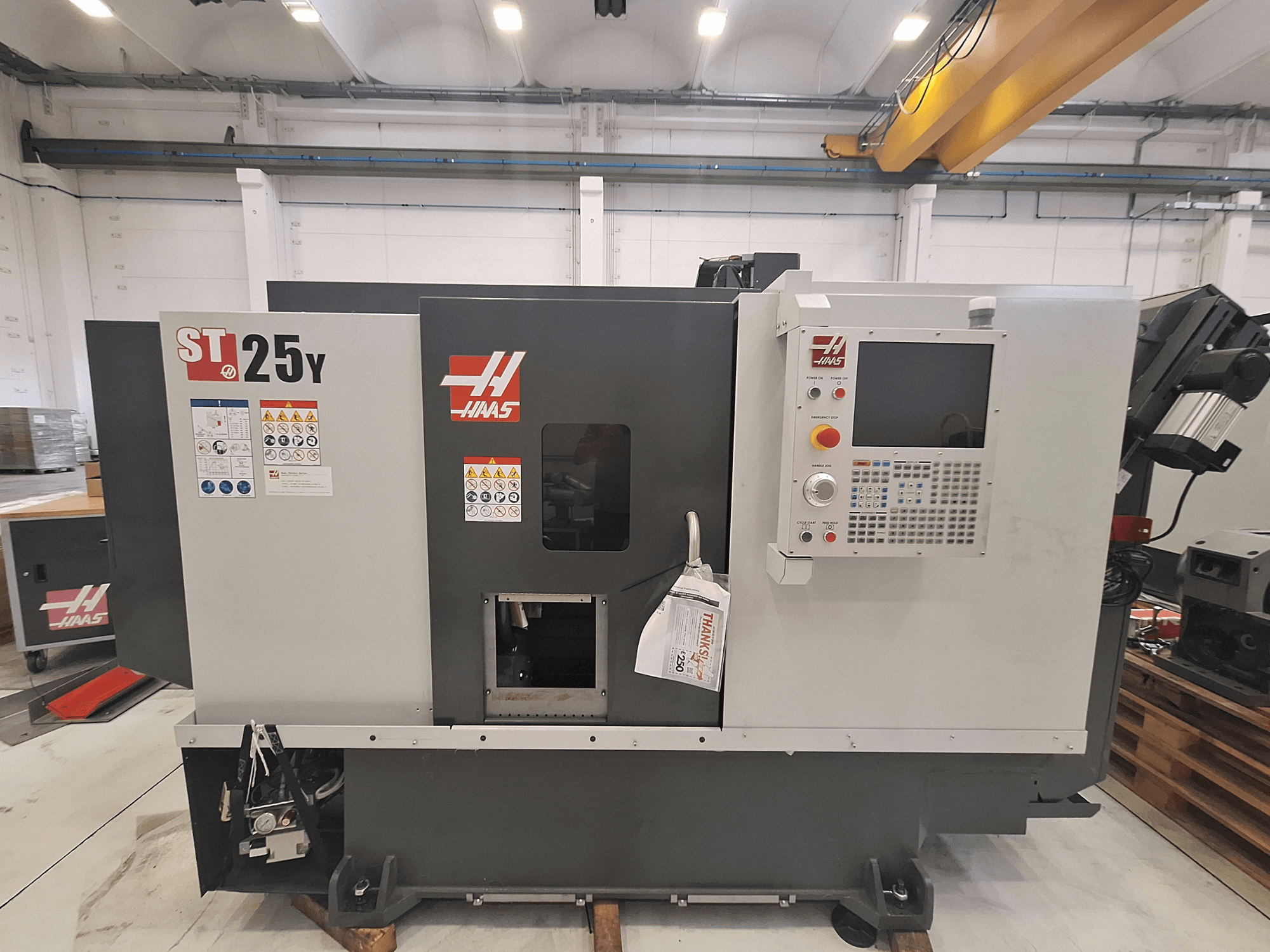 Горизонтальный токарный станок Haas ST-25Y, вид спереди, с панелью управления и предупреждающими надписями. Идеально подходит для прецизионной обработки.
