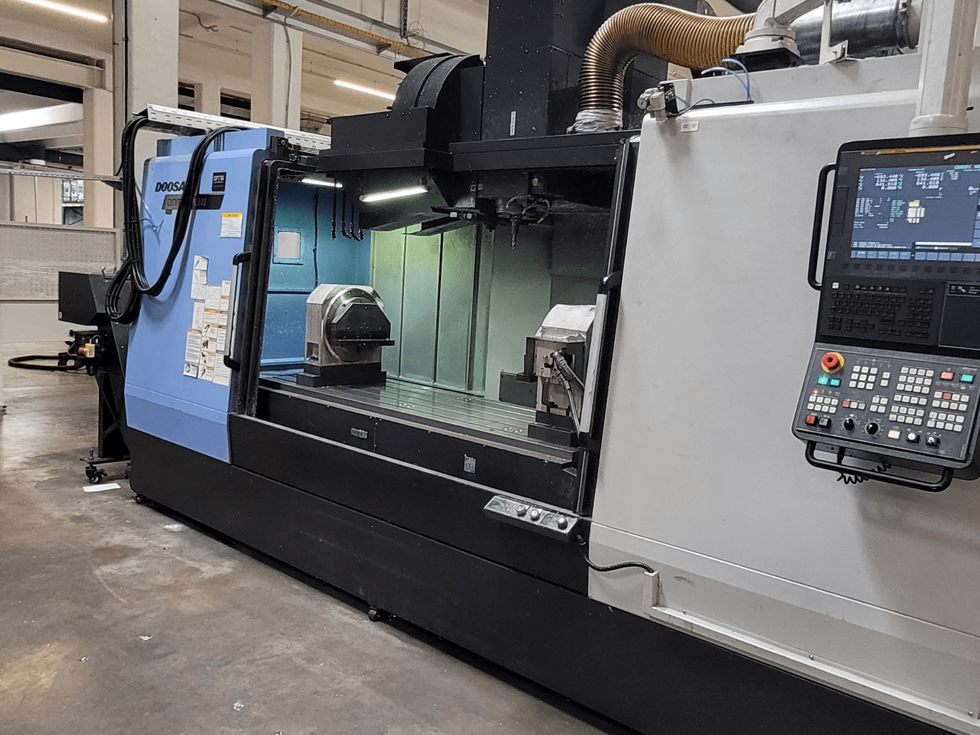 Вертикальный обрабатывающий центр DOOSAN DNM 6700 XL, вид спереди с панелью управления, рабочим столом и зоной обработки.