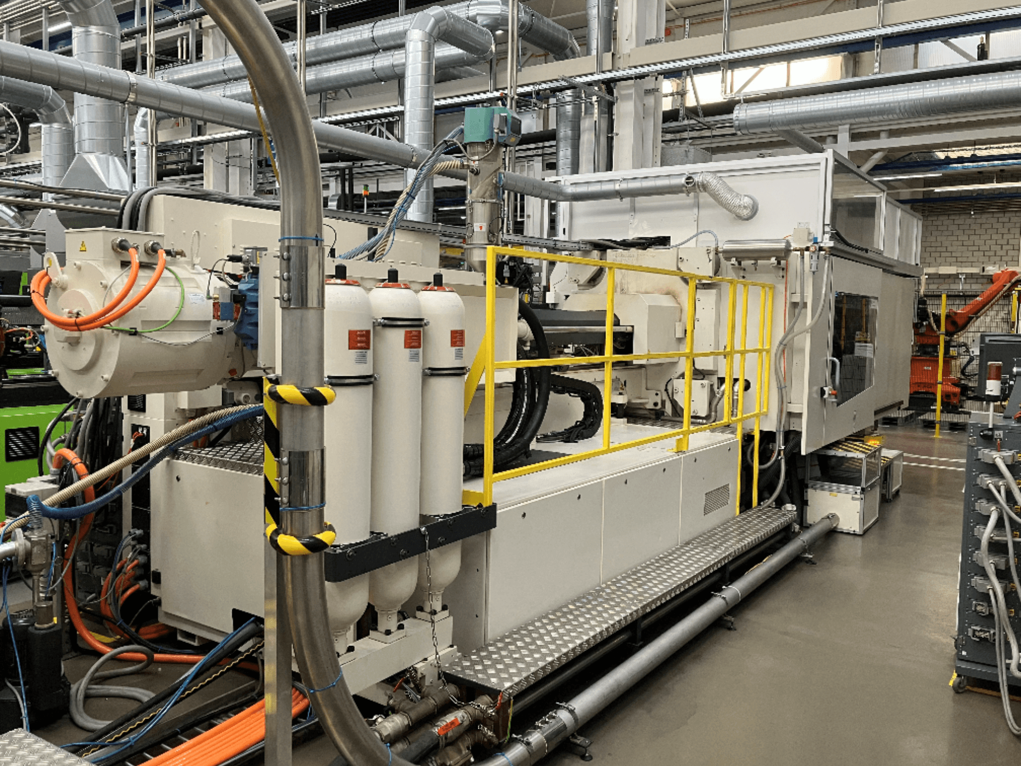 Промышленная машина с белым и серым корпусом, множеством шлангов и фильтрующих баков; вид сбоку, демонстрирующий рабочее оборудование.