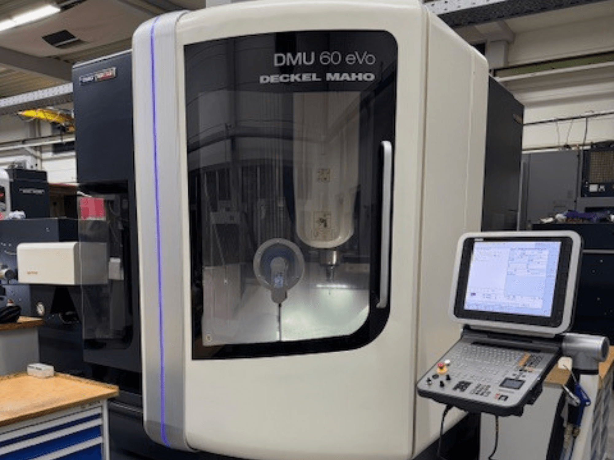 DMU 60 eVo от DECKEL MAHO, вид спереди на фрезерный станок с ЧПУ с панелью управления и экраном, демонстрирующий прецизионные компоненты.