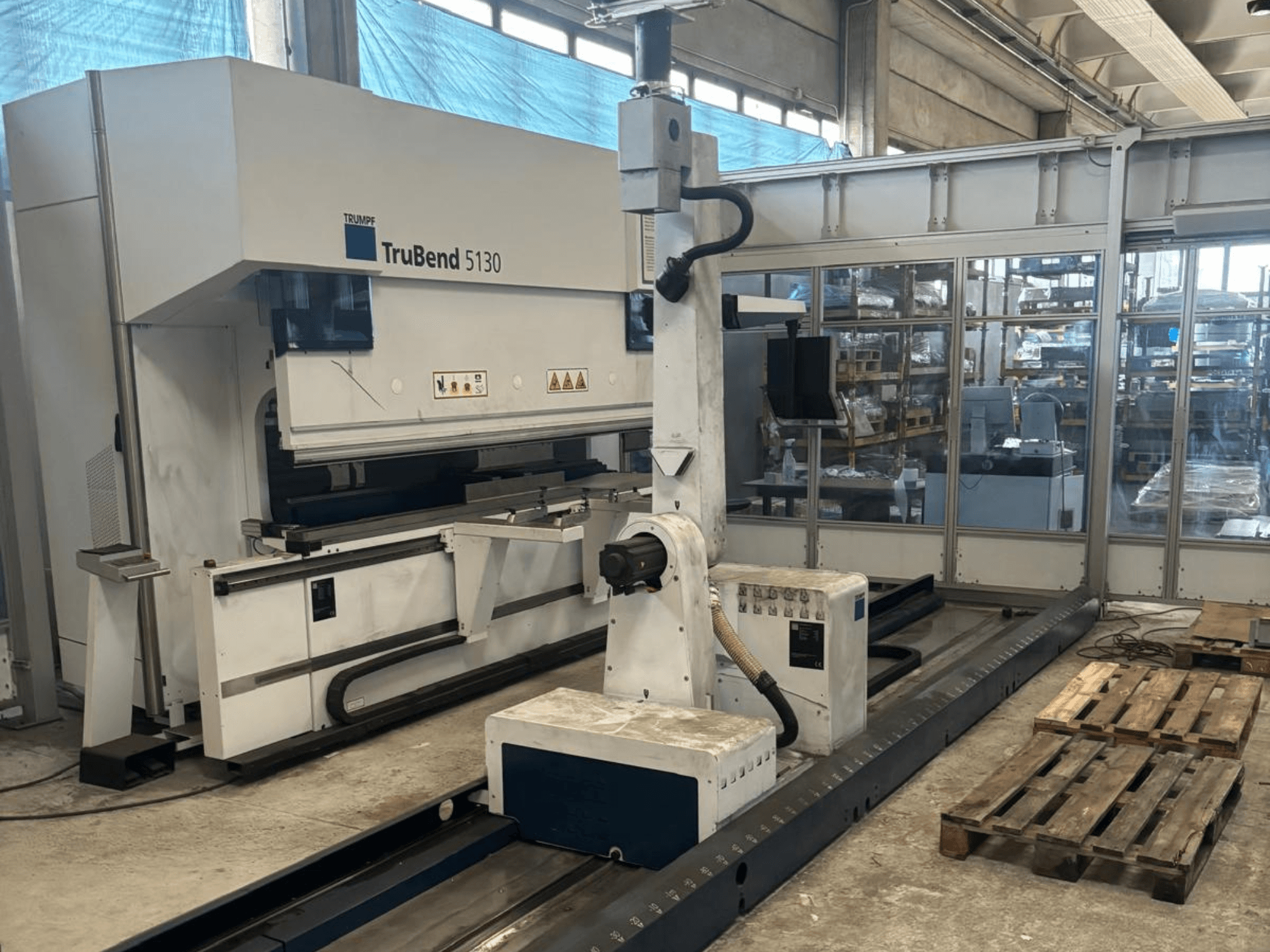 Гибочный станок TruBend 5130 компании Trumpf, вид спереди, с панелью управления и поддонами на заводе.