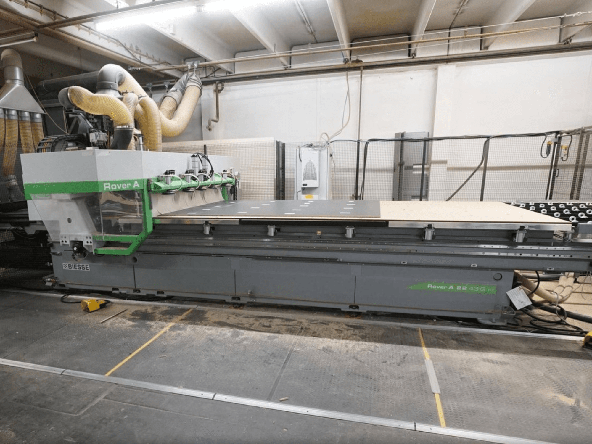 Центр обработки дерева с ЧПУ BIESSE Rover A FT 2243, вид спереди, оснащен большим рабочим столом и системой крепления инструментов.