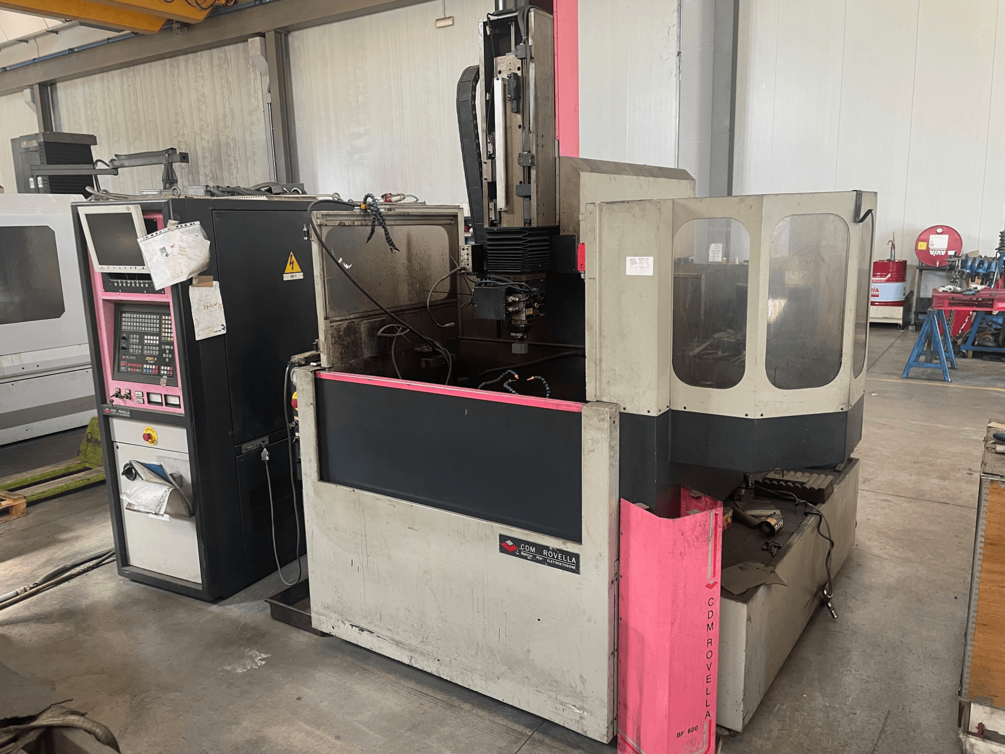 Обрабатывающий центр CDM Rovella BF 800, вид сбоку с изображением панели управления, пылезащитного кожуха и промышленной установки.