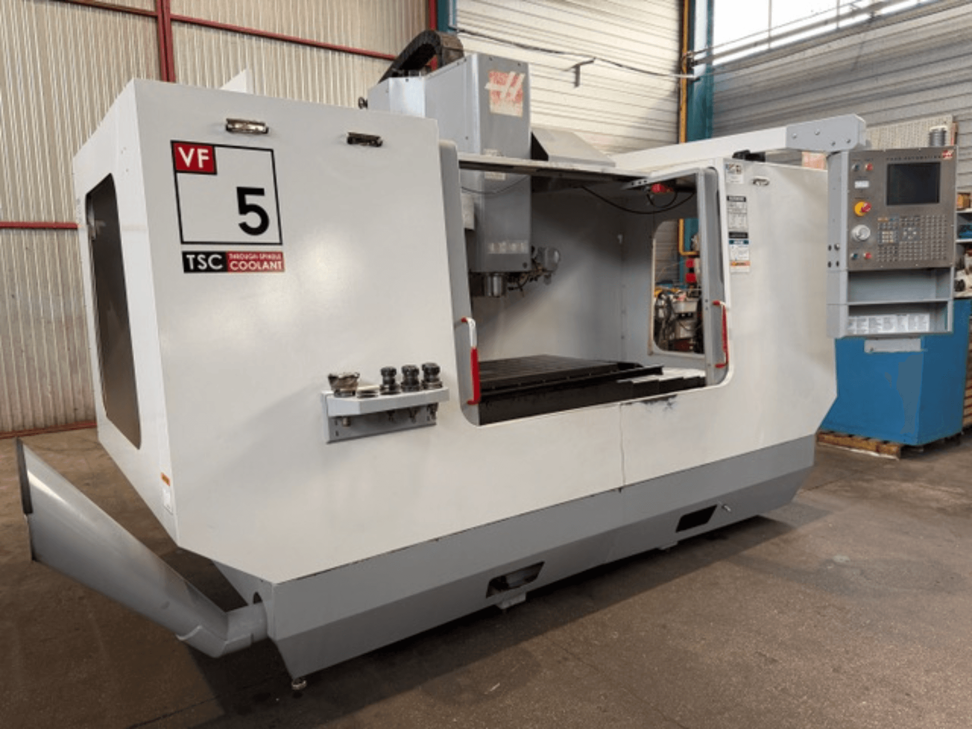 Вертикальный обрабатывающий центр HAAS VF5-HE, вид спереди, на котором видны система охлаждения TSC и панель управления оператора.