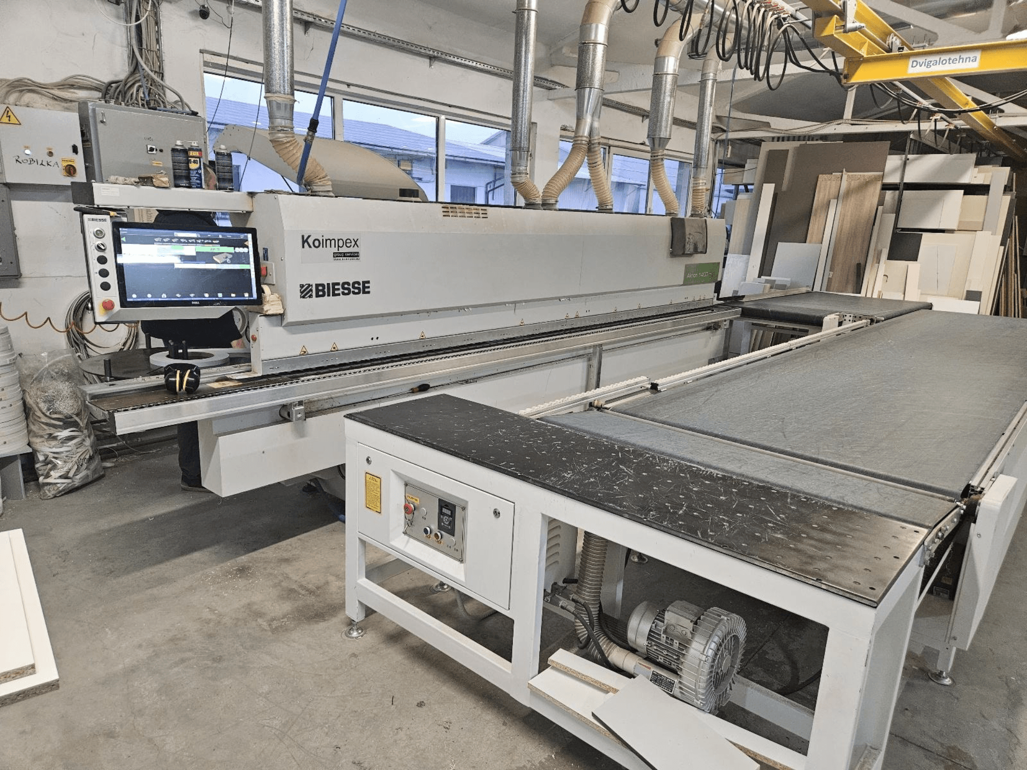 Кромкооблицовочный станок BIESSE Akron 1440 в мастерской, вид сбоку на панель управления и конвейерную ленту.