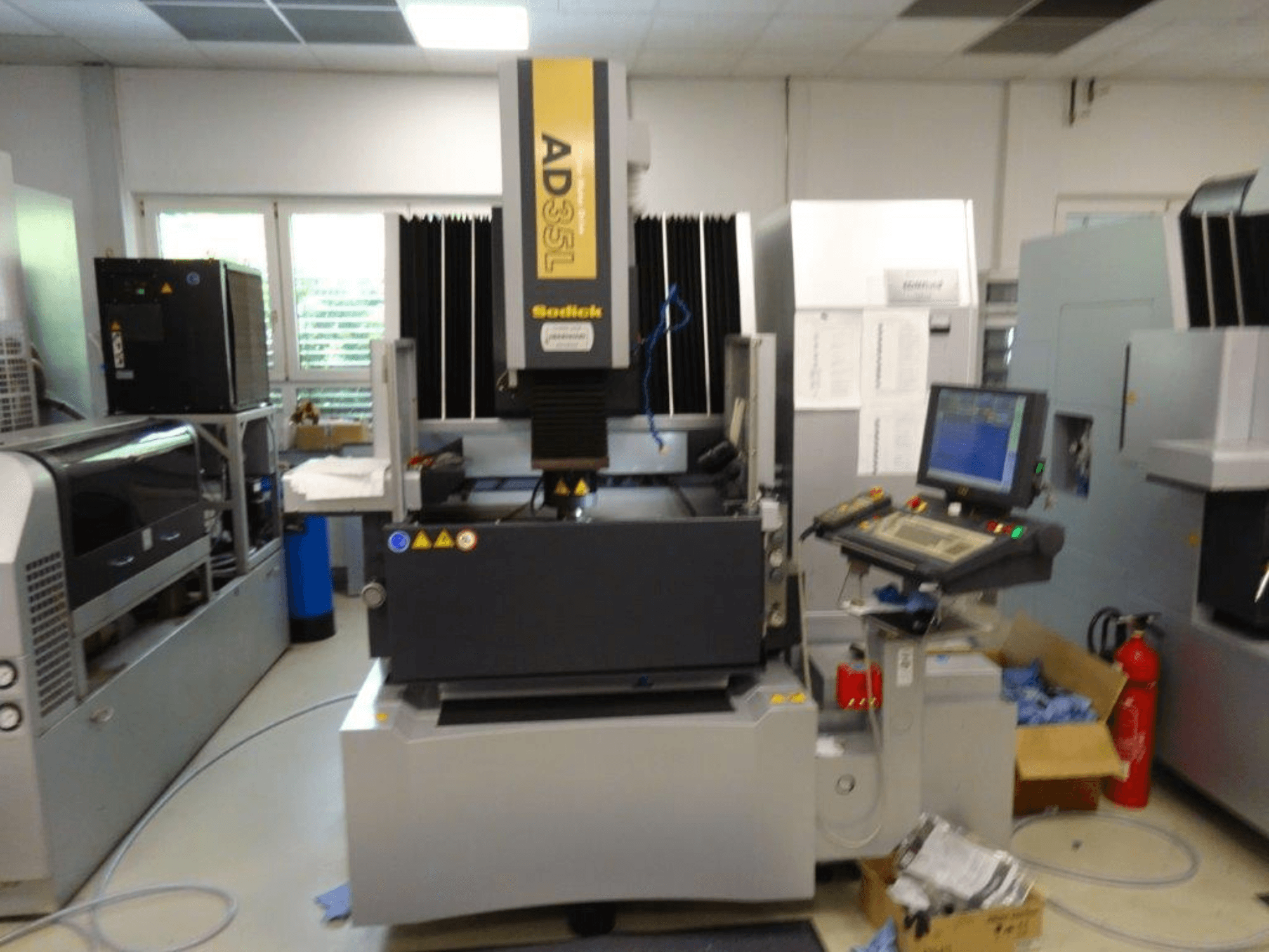 Станок с ЧПУ Sodick AD35L с видом спереди, с панелью управления, блоком охлаждения и индикаторами безопасности.