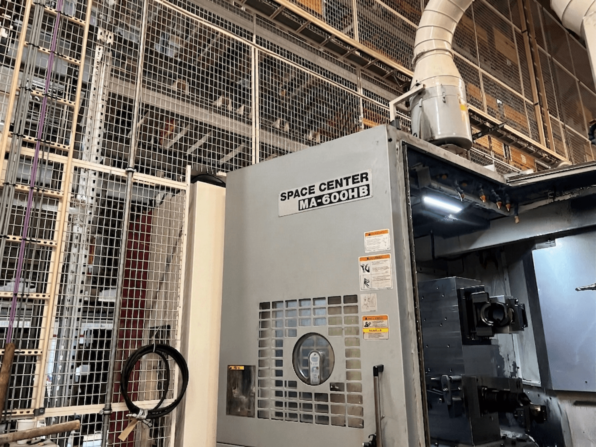 Горизонтальный обрабатывающий центр Okuma MA-600HB, вид спереди, видна панель управления и сопла охлаждающей жидкости.