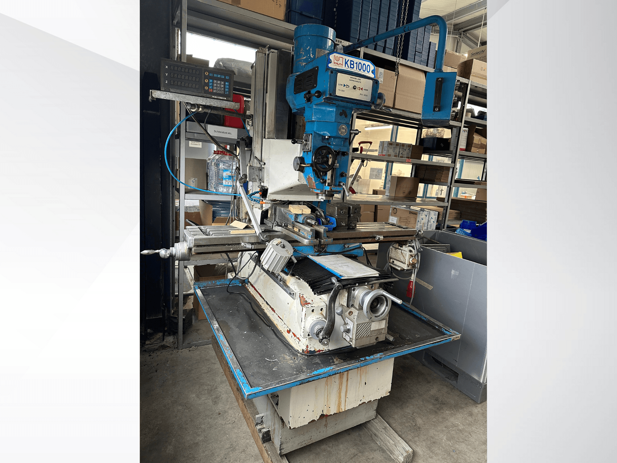 Вертикально-фрезерный станок KB1000 с цифровым дисплеем, вид сбоку, демонстрирующий стол, шпиндель и держатель инструмента.