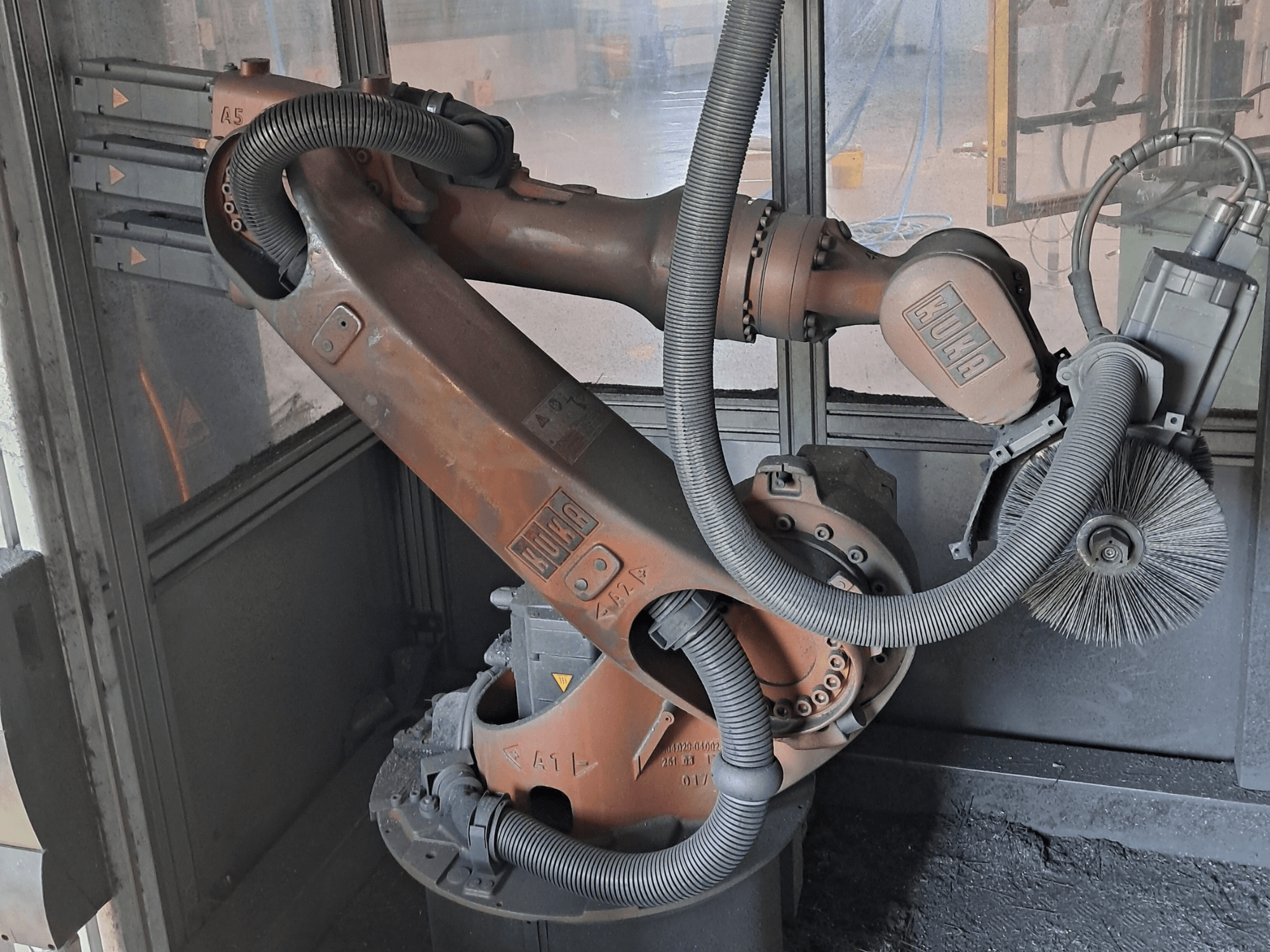 Роботизированный манипулятор KUKA KR 16-2 в виде сбоку, на котором видны кабели, щетки и механические соединения, установленный в рабочей среде.