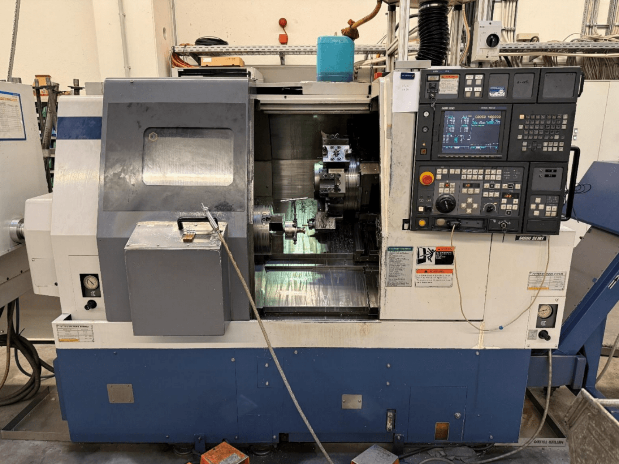 Токарно-фрезерный центр MORI SEIKI SL-250ASMC, вид спереди, на котором видны панель управления и патрон для закрепления заготовки в рабочем состоянии.