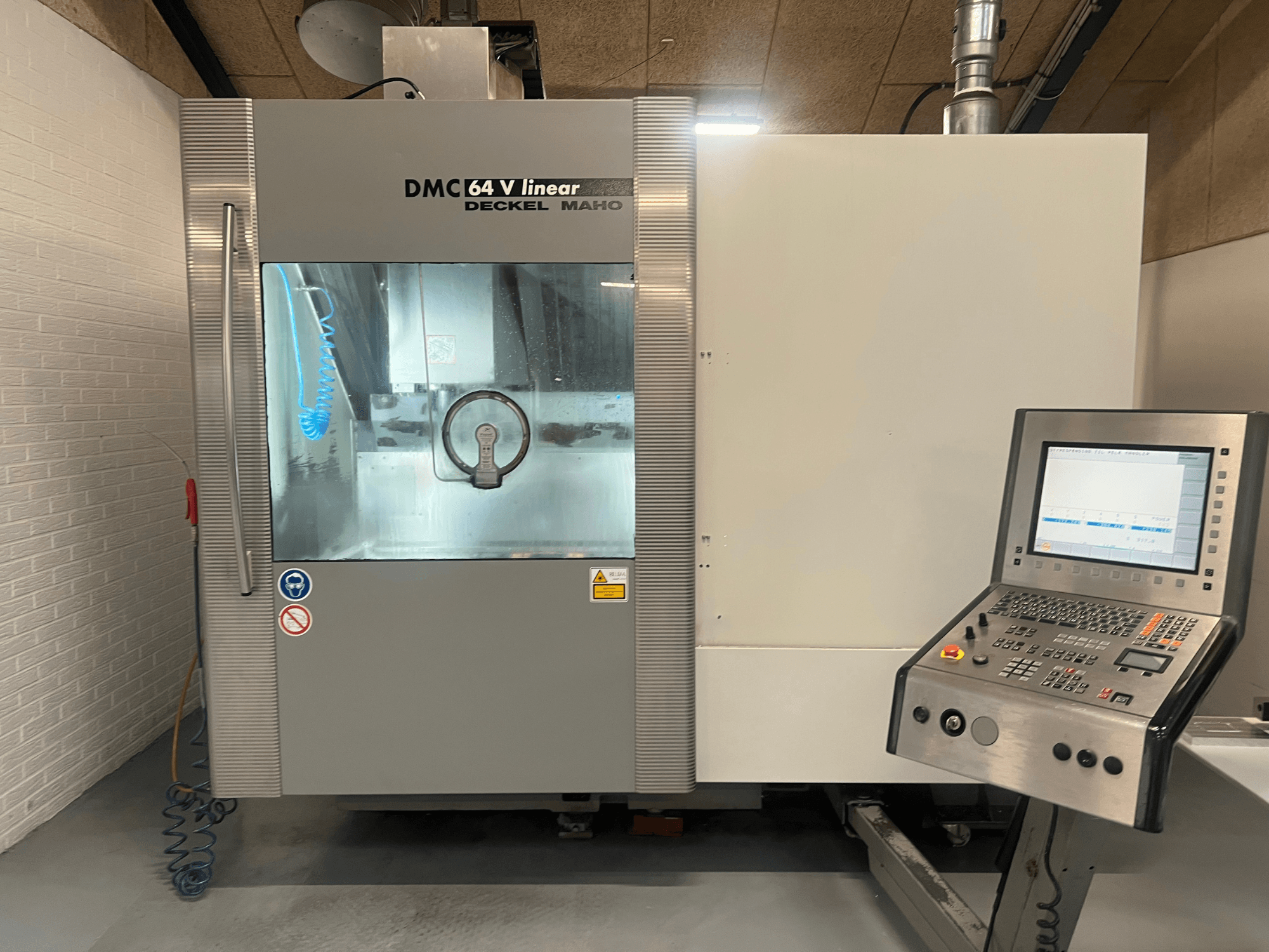 DMC 64 V Linear от Deckel Maho, вид спереди на обрабатывающий центр с ЧПУ с панелью управления и соплом для подачи СОЖ.