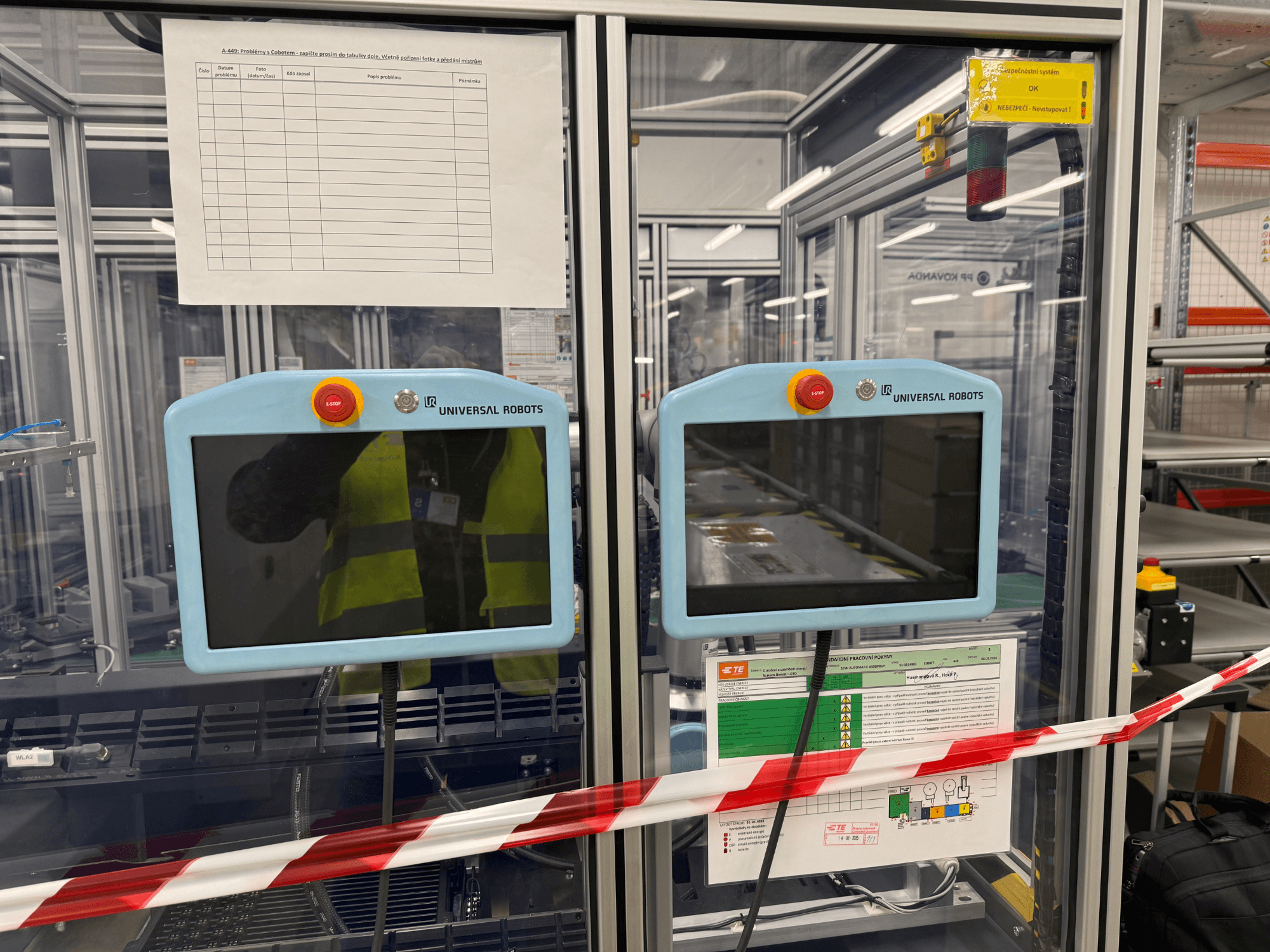 Панель управления для манипулятора Universal Robots UR5 e с двумя мониторами, кнопками аварийной остановки и инструкцией по безопасности.