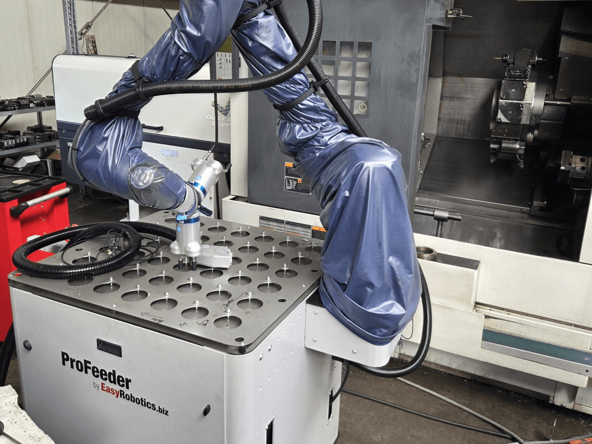Коллаборативный робот EASYROBOTICS ProFeeder вид спереди, рука робота расположена над перфорированным металлическим столом.