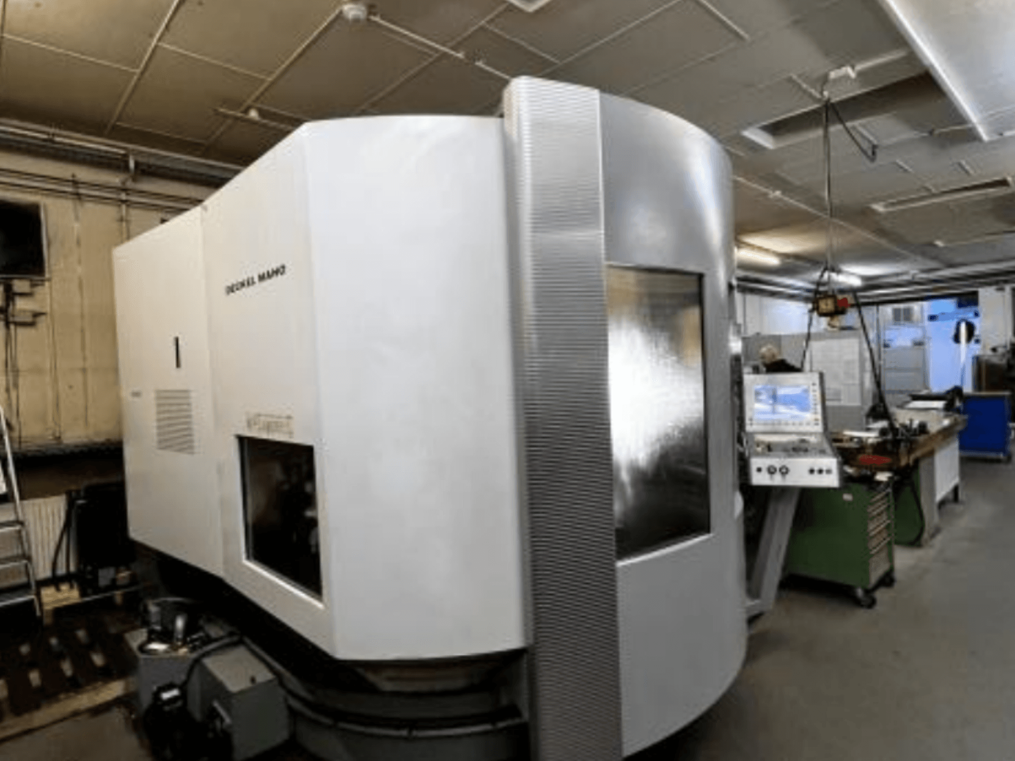 Станок с ЧПУ SODICK MAKO в мастерской, вид сбоку, на заднем плане видна панель управления и рабочая зона.