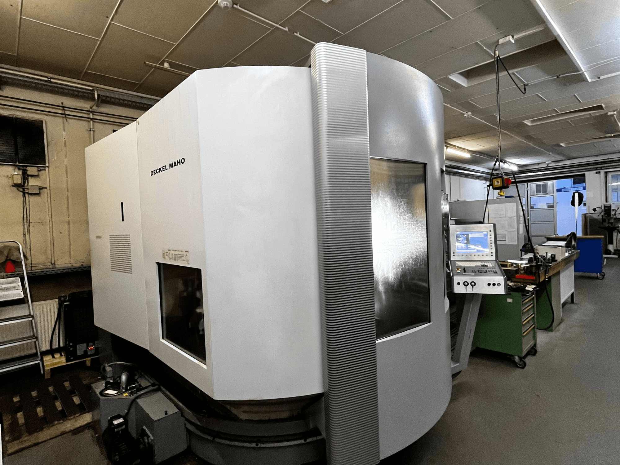 Станок с ЧПУ Deckel Maho, вид спереди, белая внешняя сторона, видна панель управления, установка в мастерской.