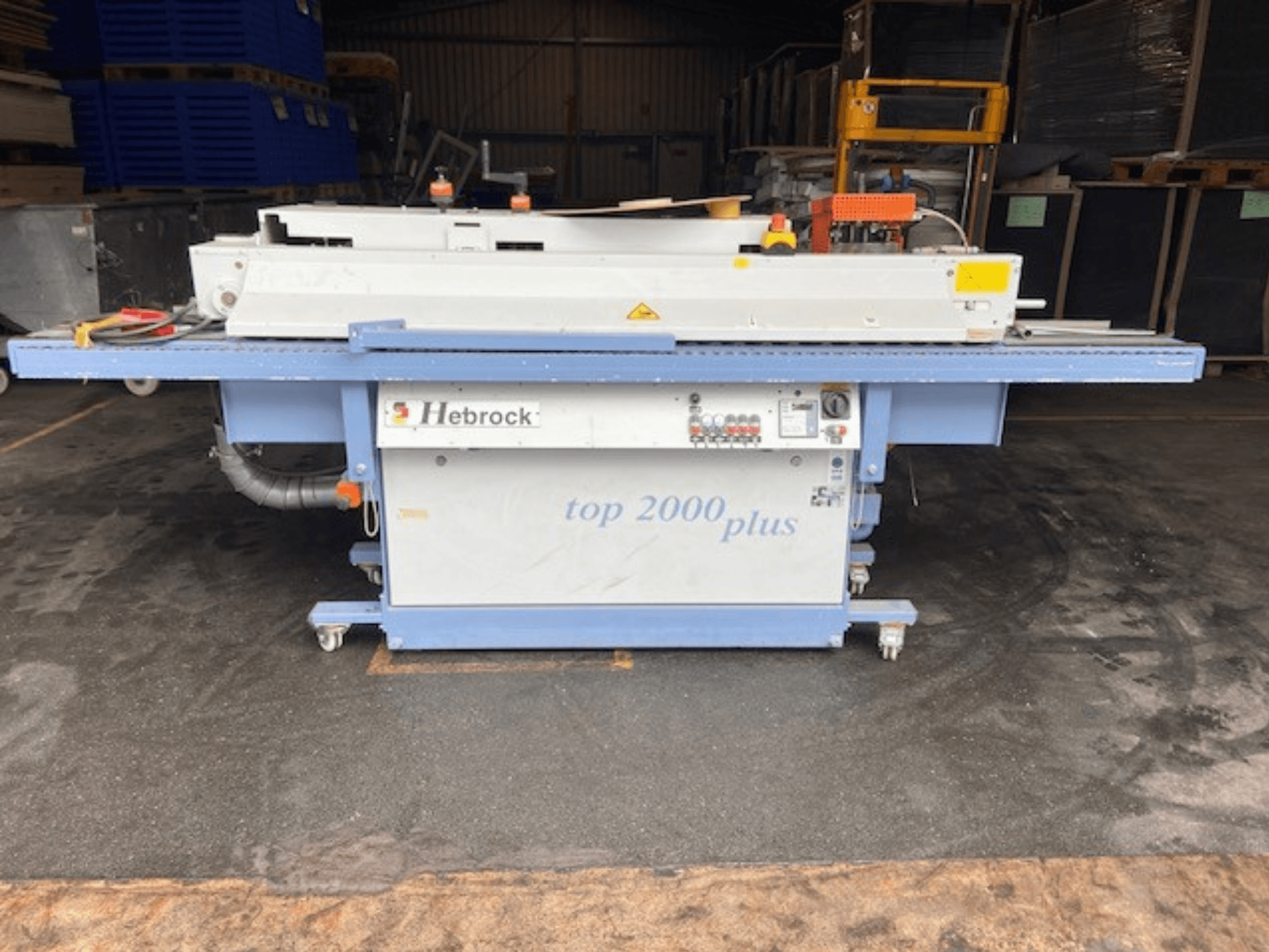 Hebrock Top 2000 Plus, вид спереди; промышленная электрическая машина с панелью управления, колесами для передвижения и наклейками безопасности.