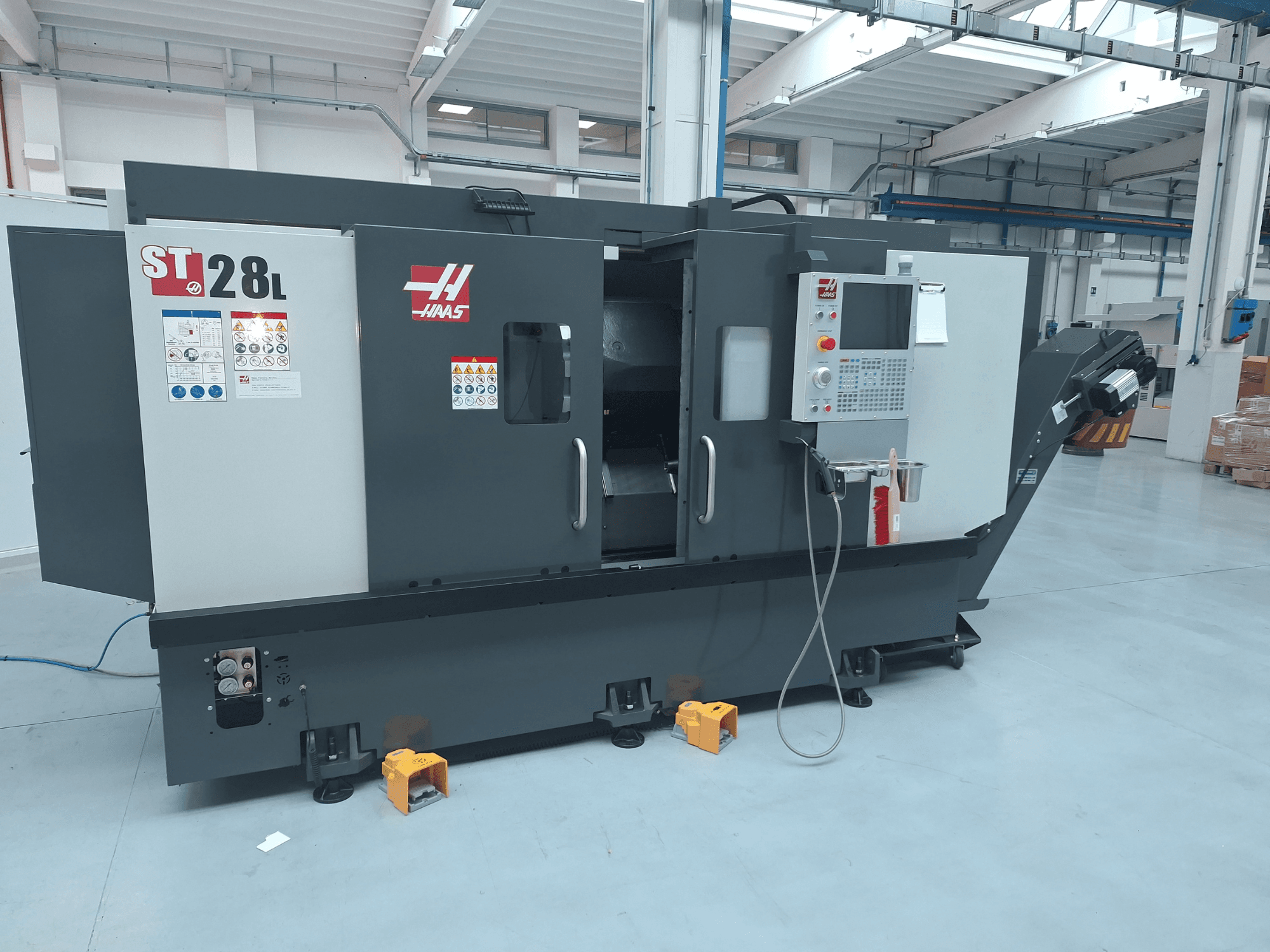 Горизонтальный токарный станок Haas ST-28L в виде сбоку: на фотографии видны панель управления, рабочие кнопки и предупреждающие надписи.
