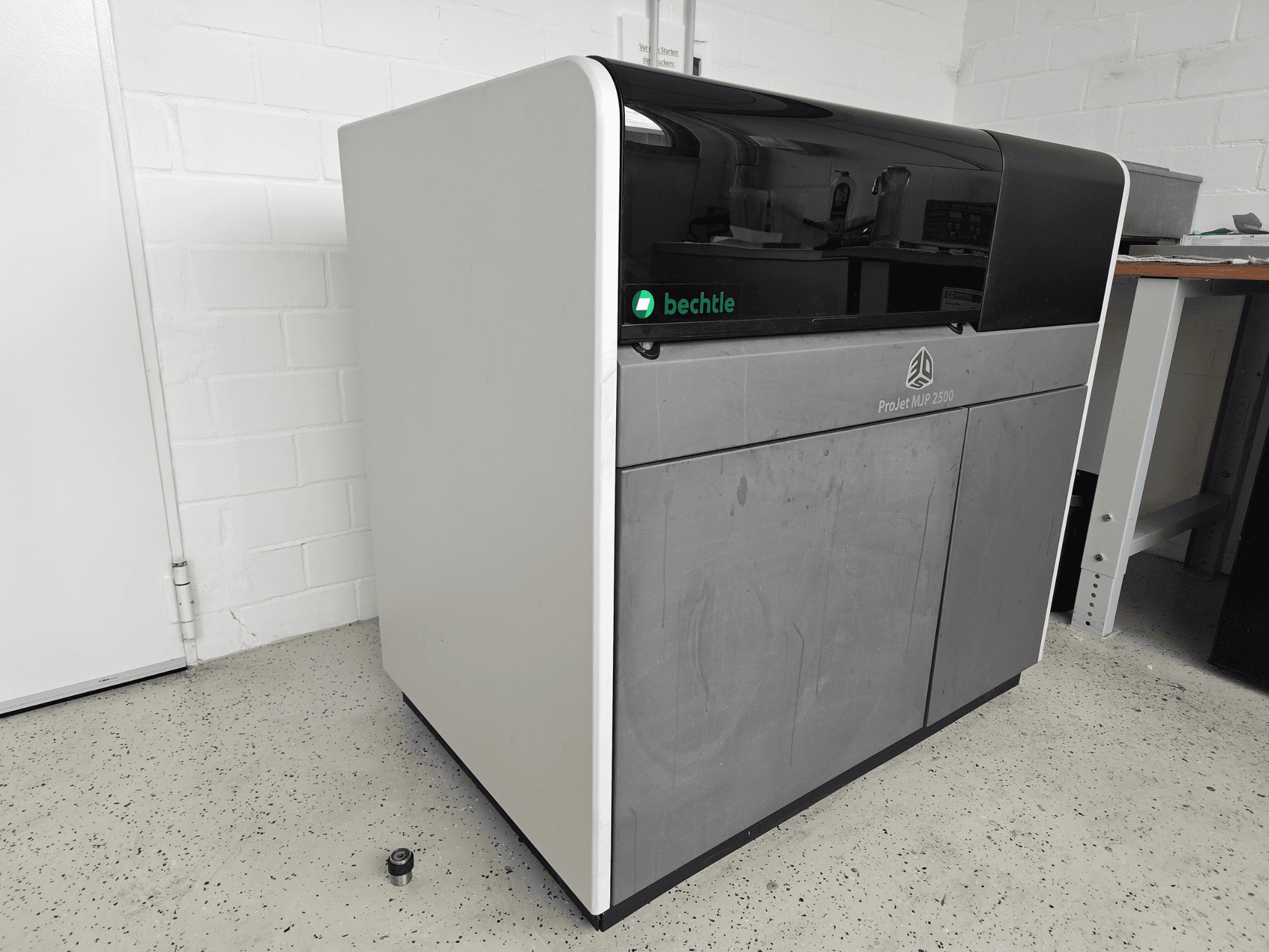 3D-принтер для печати из пластика 3D Systems ProJet MJP 2500 Plus, вид спереди; отличается лаконичным дизайном с тёмной верхней панелью и светлым корпусом.