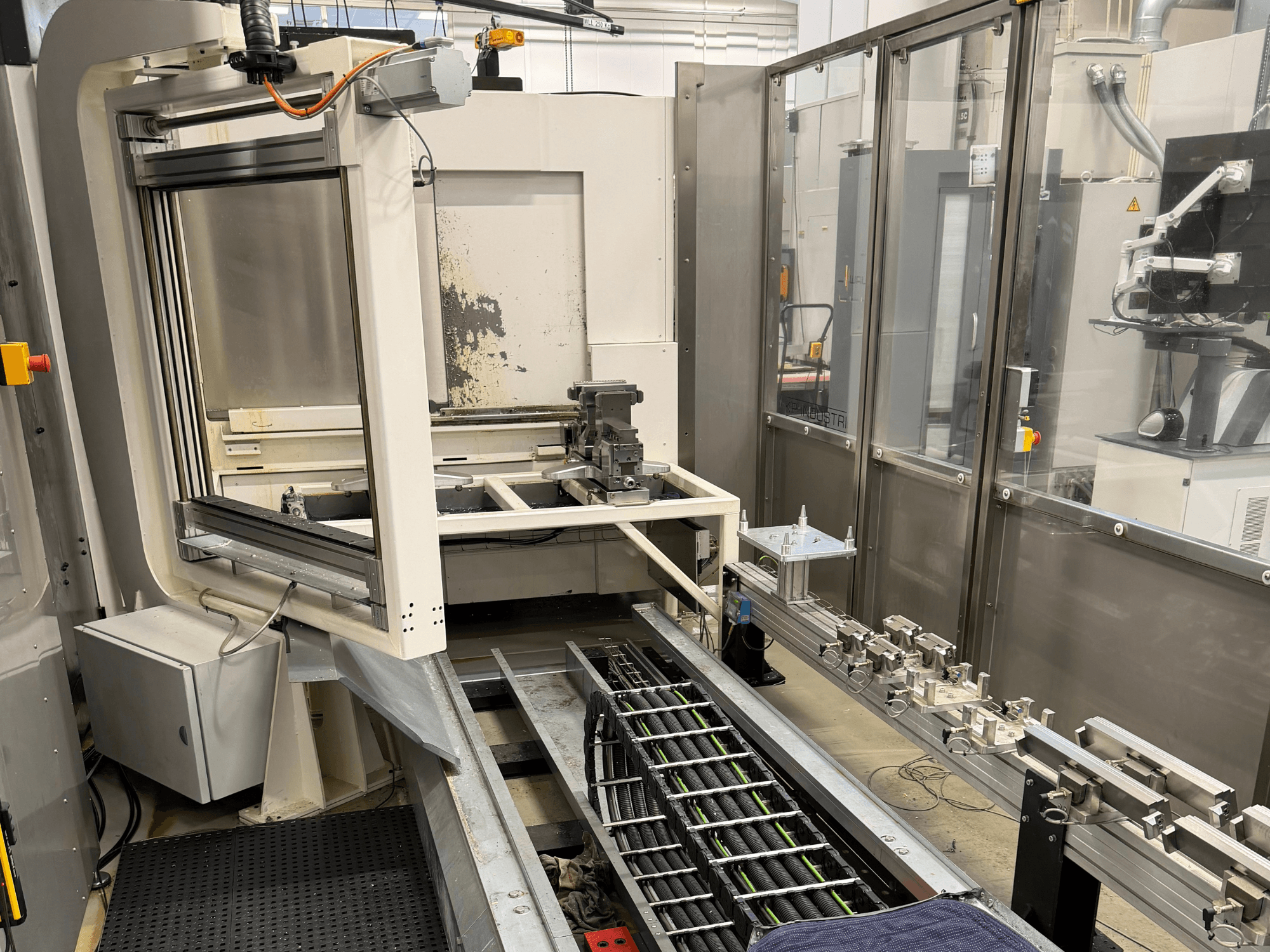 Автоматизированная промышленная рабочая станция с роботизированным манипулятором, рельсовой системой и панелью управления на виде сбоку.