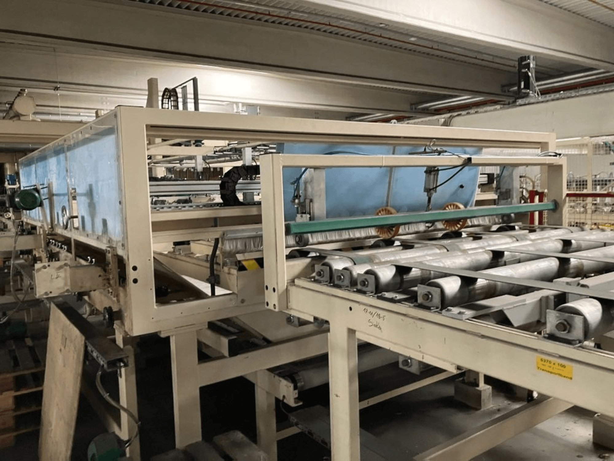 Ламинационный пресс WEMHÖNER KT-F-1E, вид сбоку, с валами и органами управления для обработки материалов на заводе.