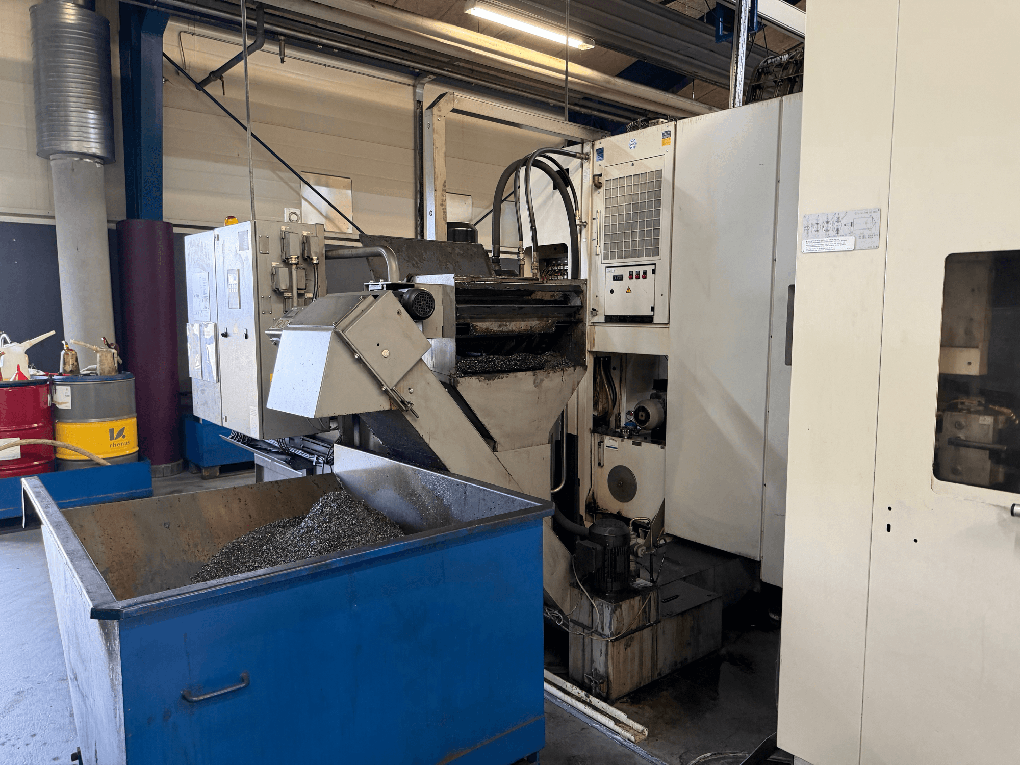 Вид спереди горизонтального обрабатывающего центра HELLER MCH 250, видны бункер для рециркуляции охлаждающей жидкости и панель управления.