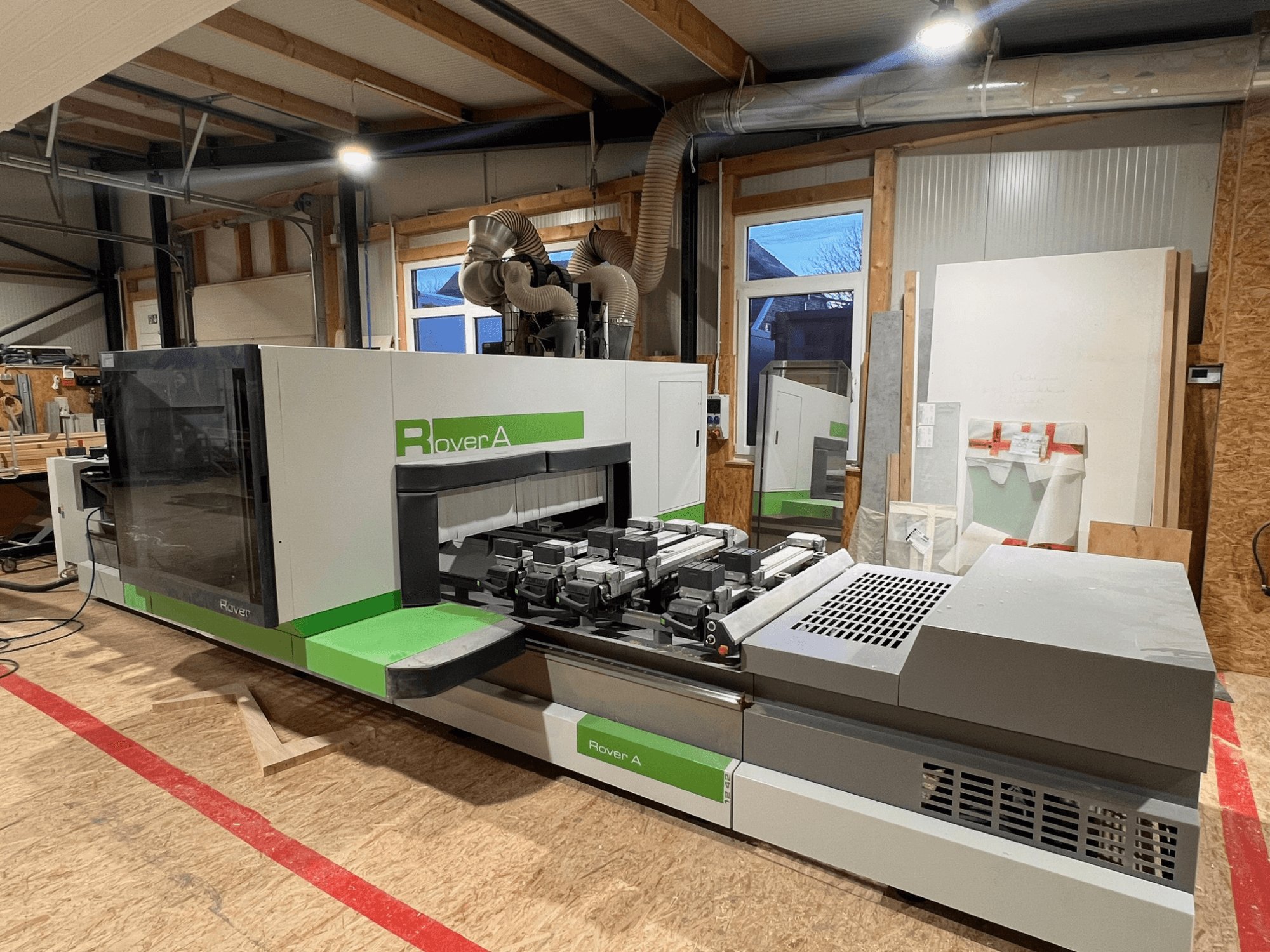 Обрабатывающий центр с ЧПУ по дереву BIESSE Rover A 1242, вид спереди, показывающий панель управления и зону резки в мастерской.