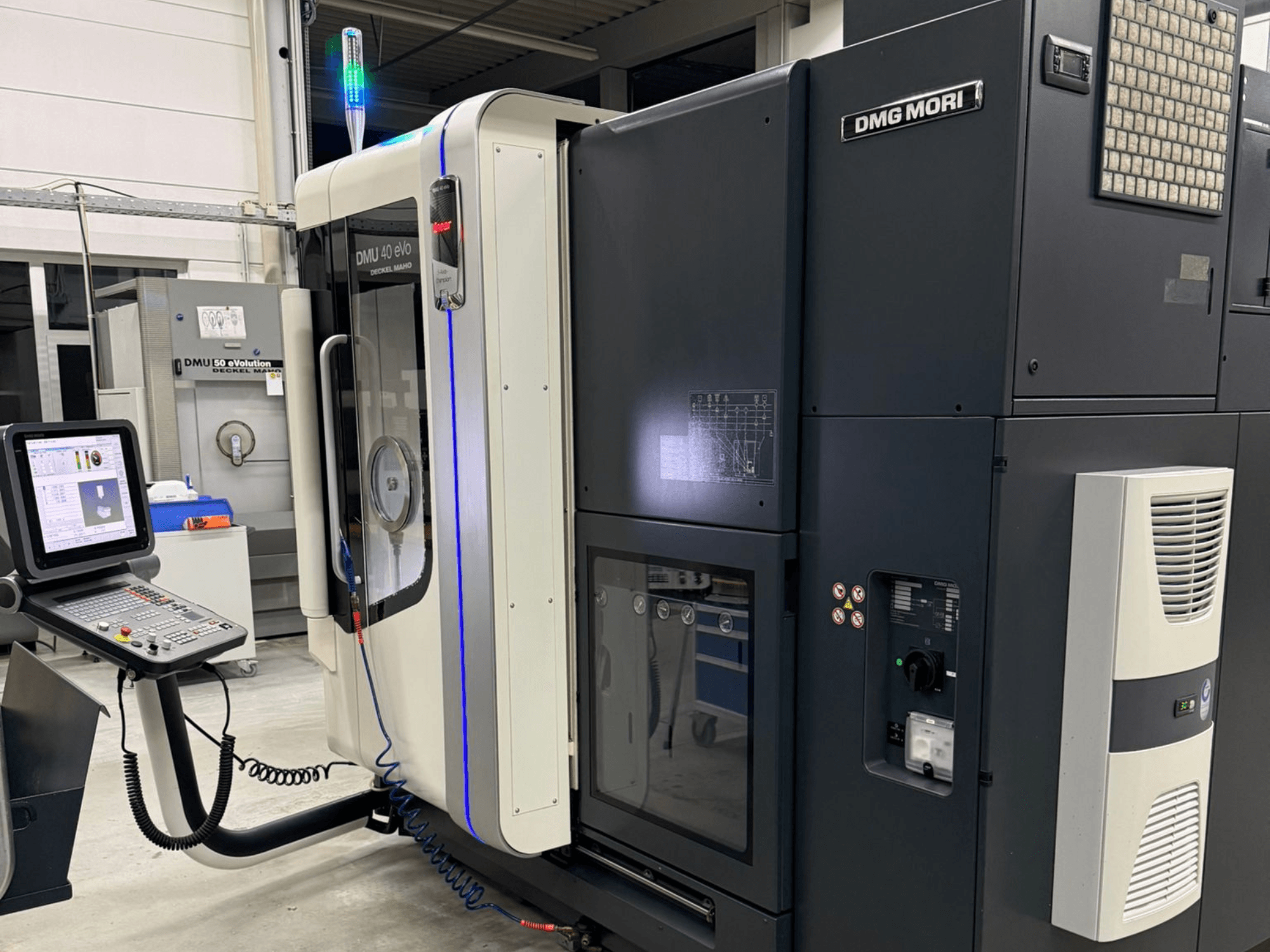 Станок DMG MORI DMU 40 eVo, вид спереди, демонстрирующий органы управления, светодиодные индикаторы и элегантный дизайн, подчеркивающий промышленные характеристики.