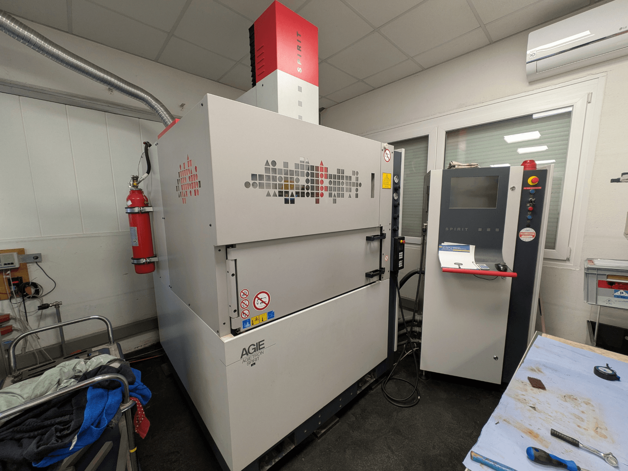 Углошлифовальный электроэрозионный станок AGIE AGIETRON SPIRIT 3, вид сбоку, демонстрирует панель управления и огнетушитель.