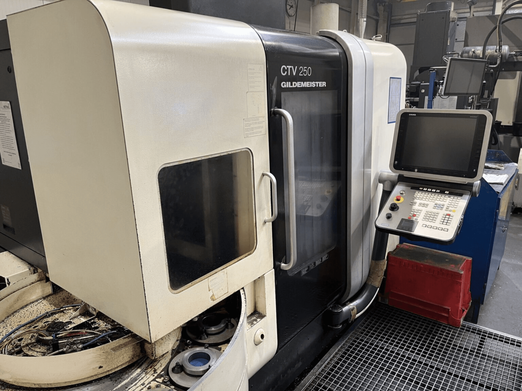 Вертикальный токарный станок DMG CTV-250 спереди, видна панель управления и рабочая зона с инструментами.