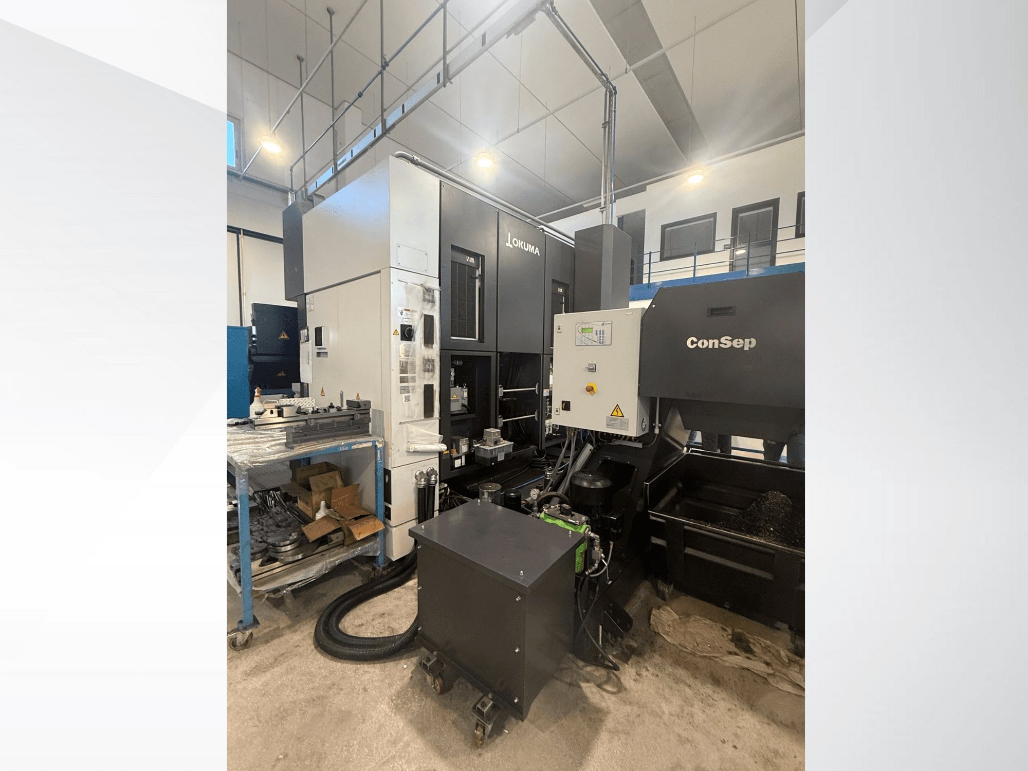 Обрабатывающий центр Okuma с блоком ConSep, вид сбоку, демонстрация органов управления и промышленного оборудования, включая бункер для металлической стружки.