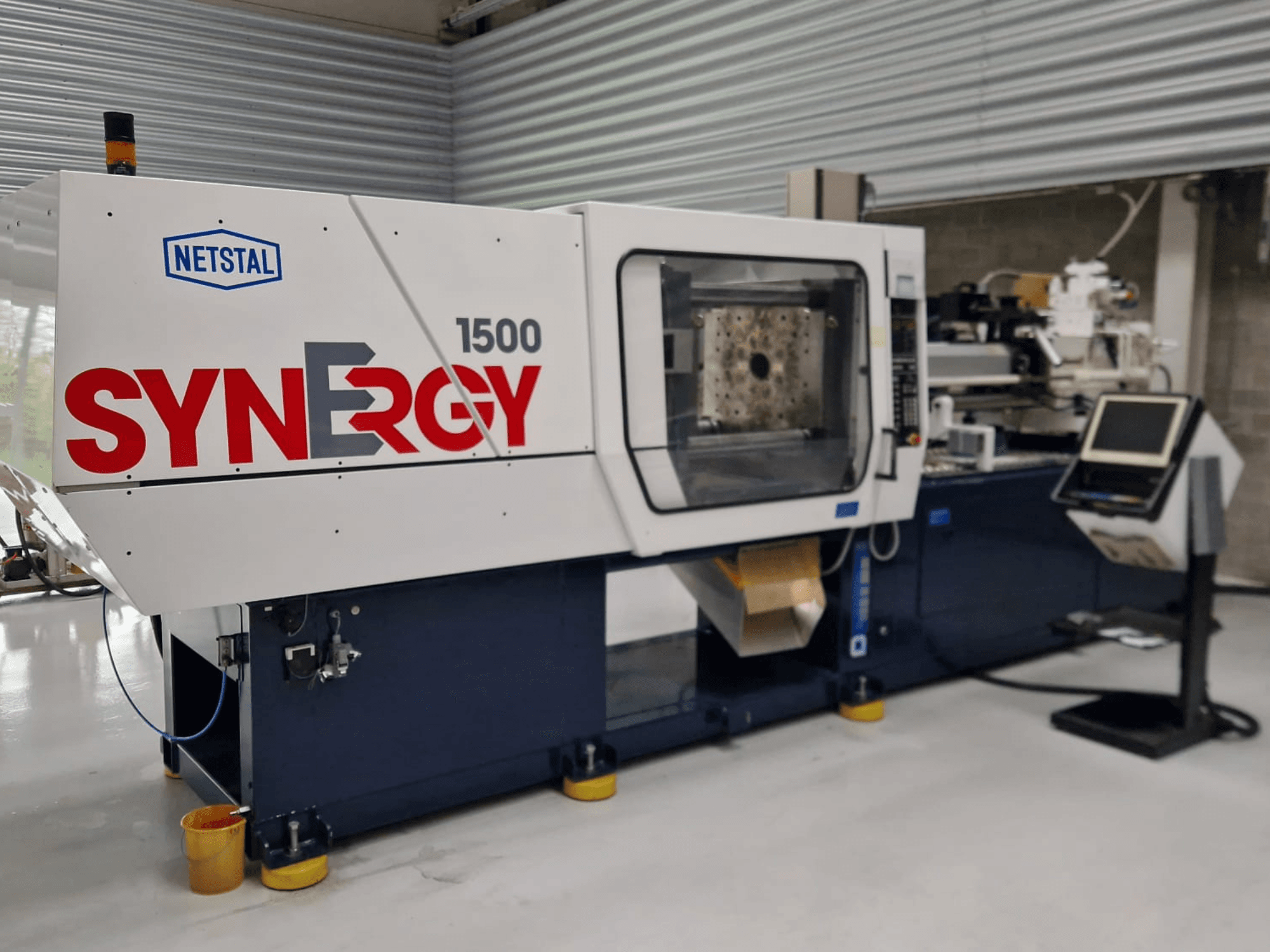 Гидравлическая машина для литья под давлением Netstal Synergy 1500-460, вид спереди, демонстрирует панель управления и открытую зону впрыска.