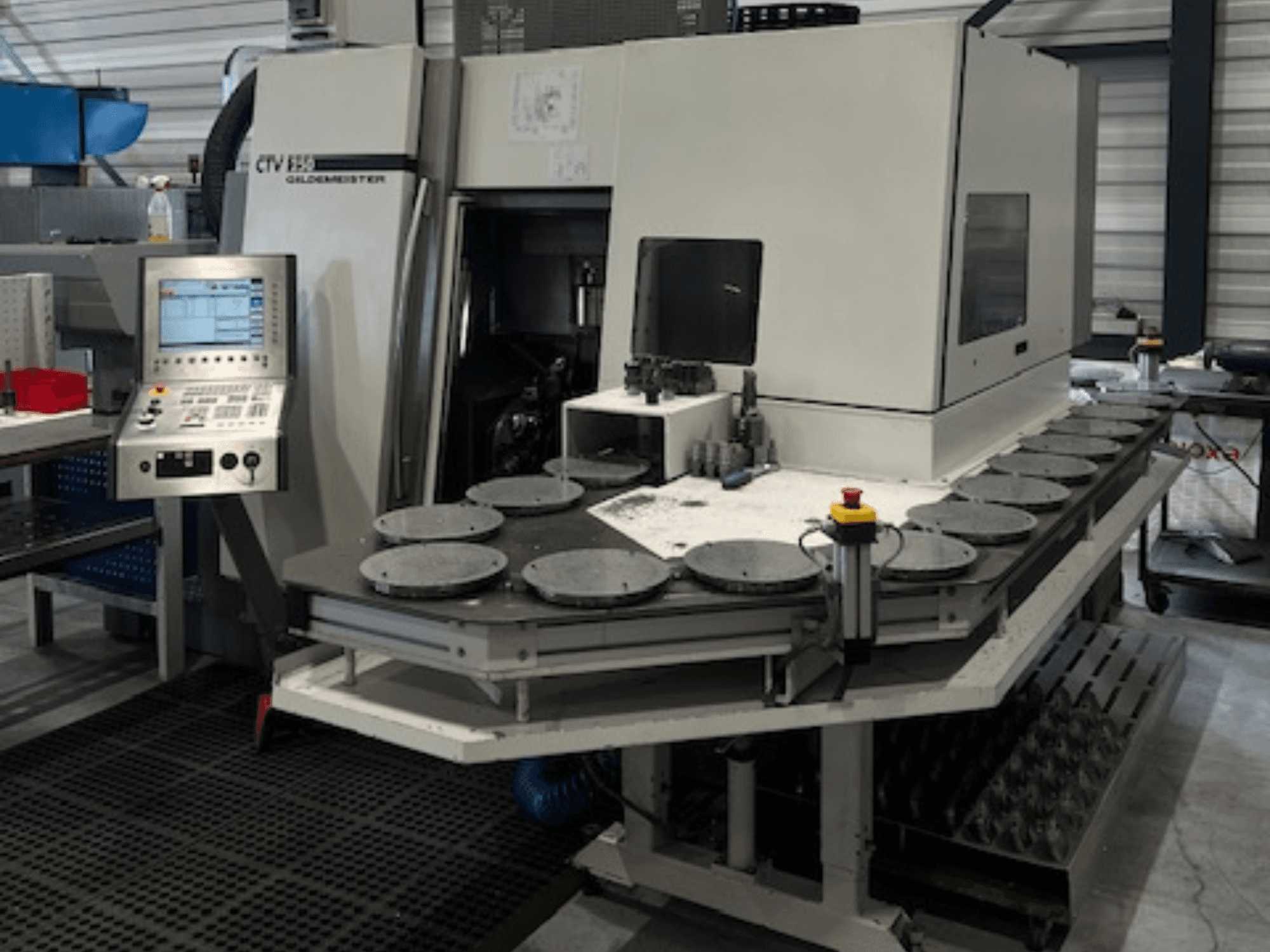 Альт. текст: CTV E33 Станок Goldmeister в мастерской, вид спереди, с панелью управления и несколькими круглыми рабочими платформами.