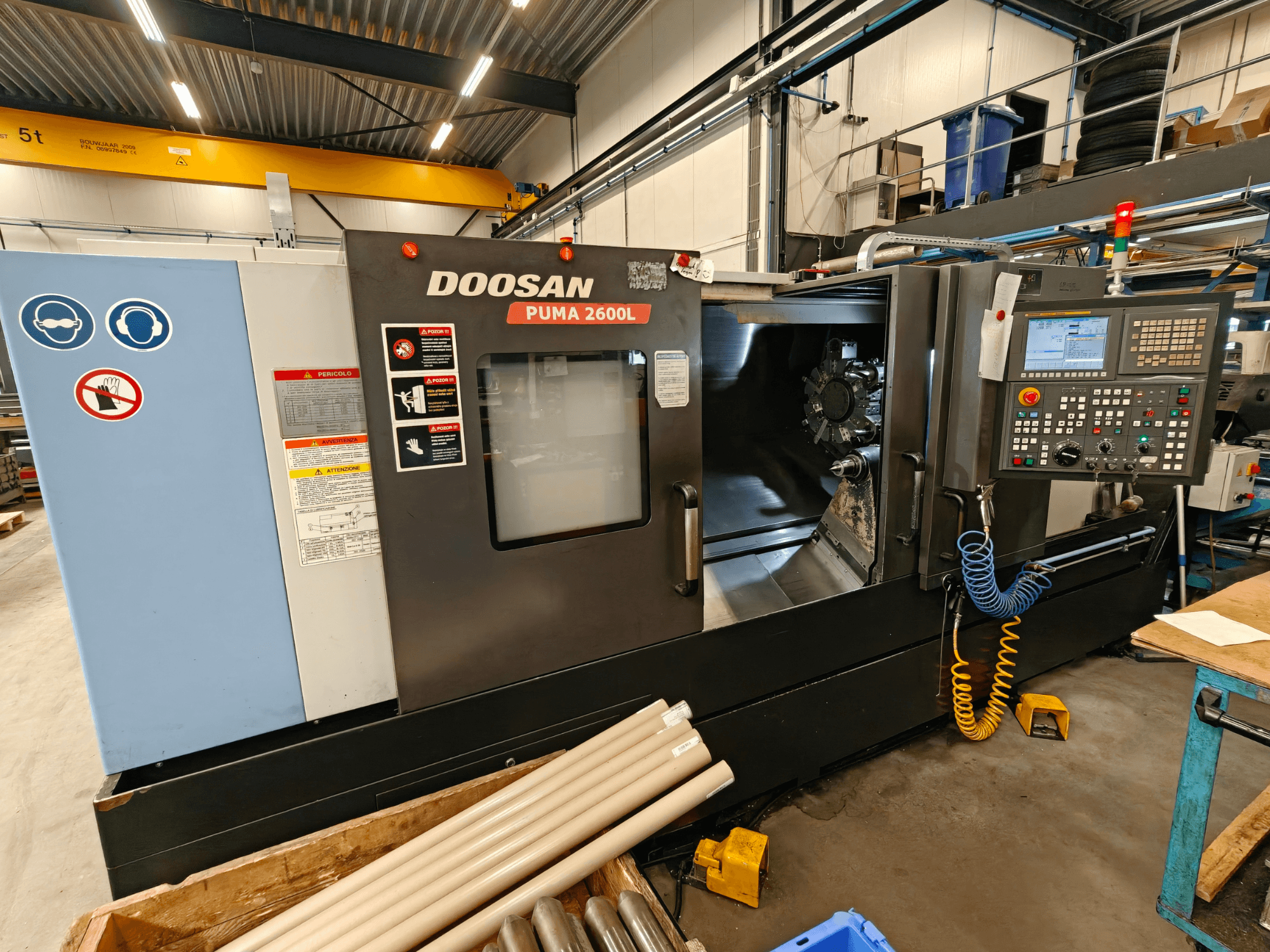 Горизонтальный токарный станок DOOSAN Puma 2600L в мастерской, вид сбоку на панель управления и область шпинделя.