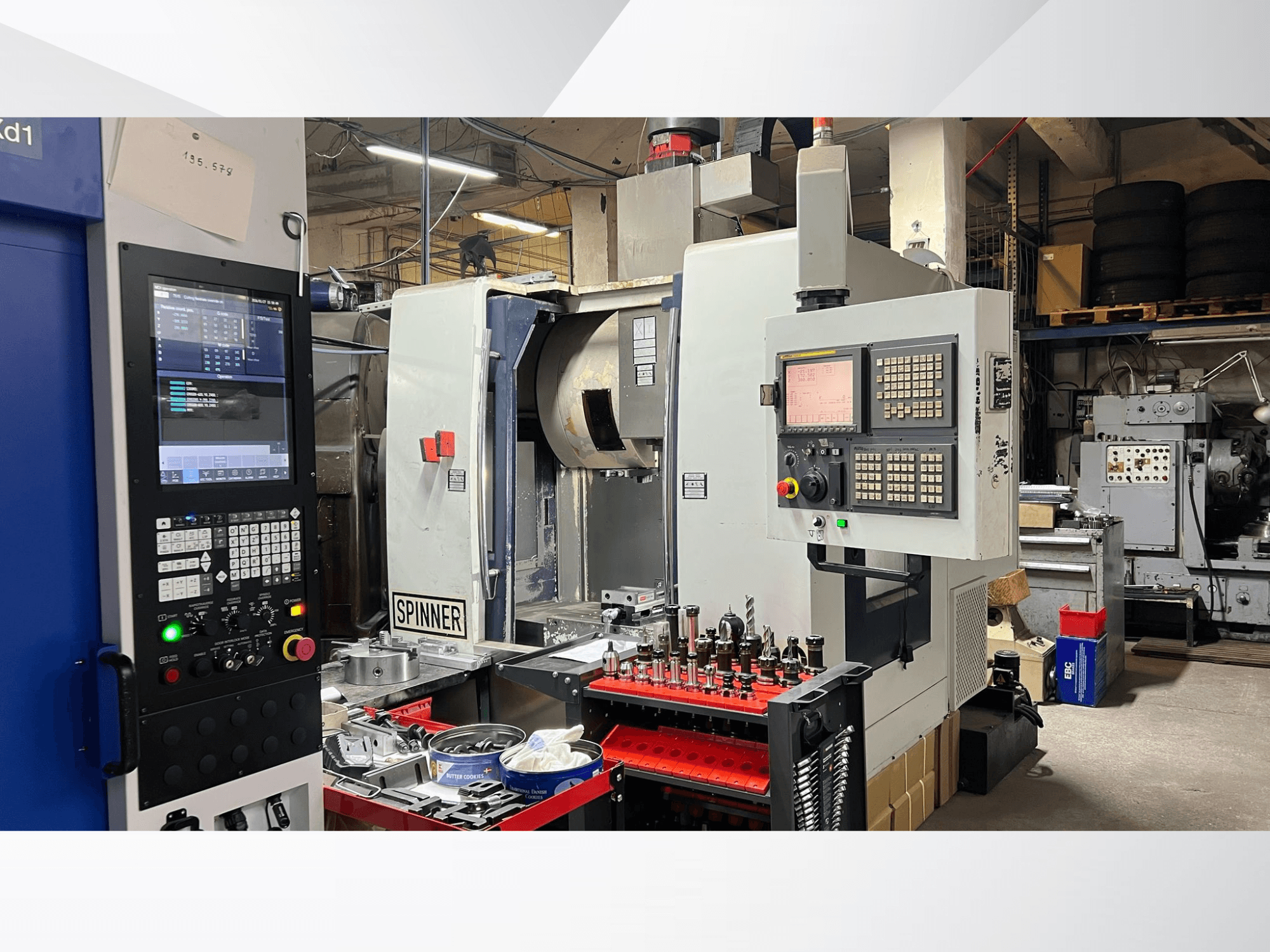 Станок с ЧПУ с панелью управления, инструментами и заготовками, вид спереди в условиях мастерской.