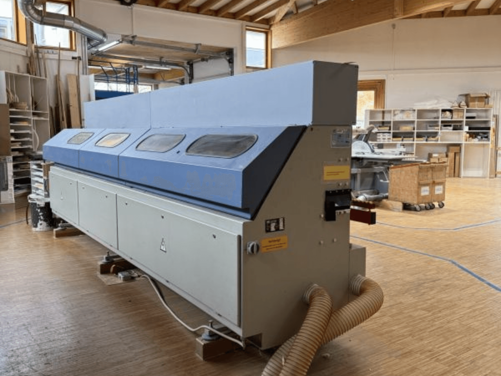 Кромкооблицовочный станок OTT Pacific V6-F показан с боковой стороны; имеет длинный синий верх и панель управления с креплением для шланга.