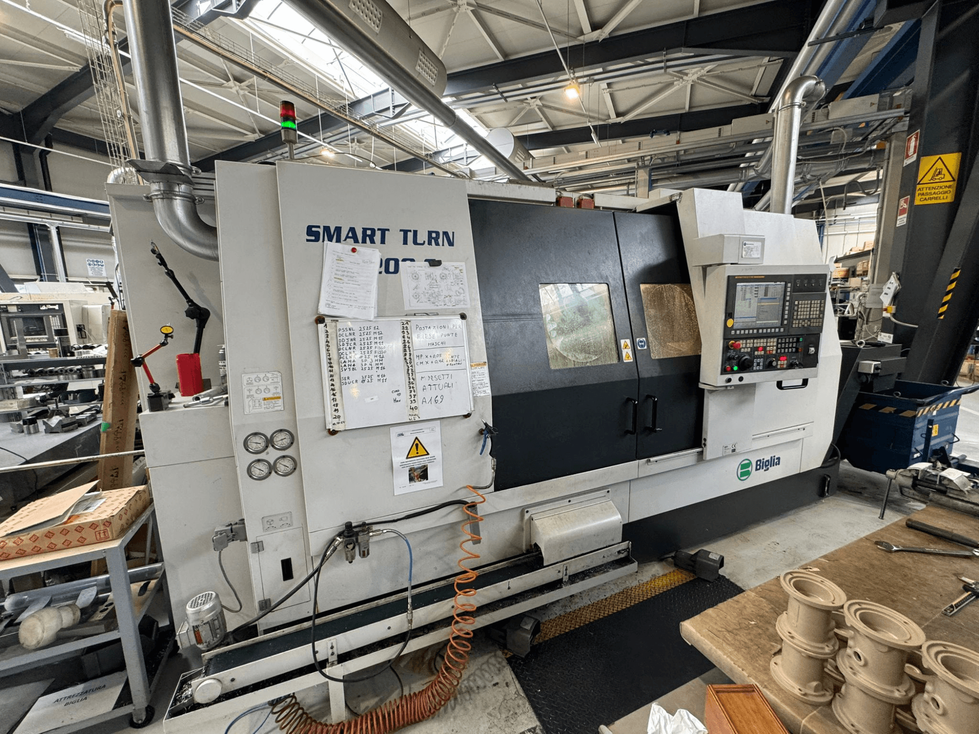 Токарно-фрезерный центр Biglia Smart Turn B1200S в мастерской, с панелью управления, манометрами и индикаторами безопасности.