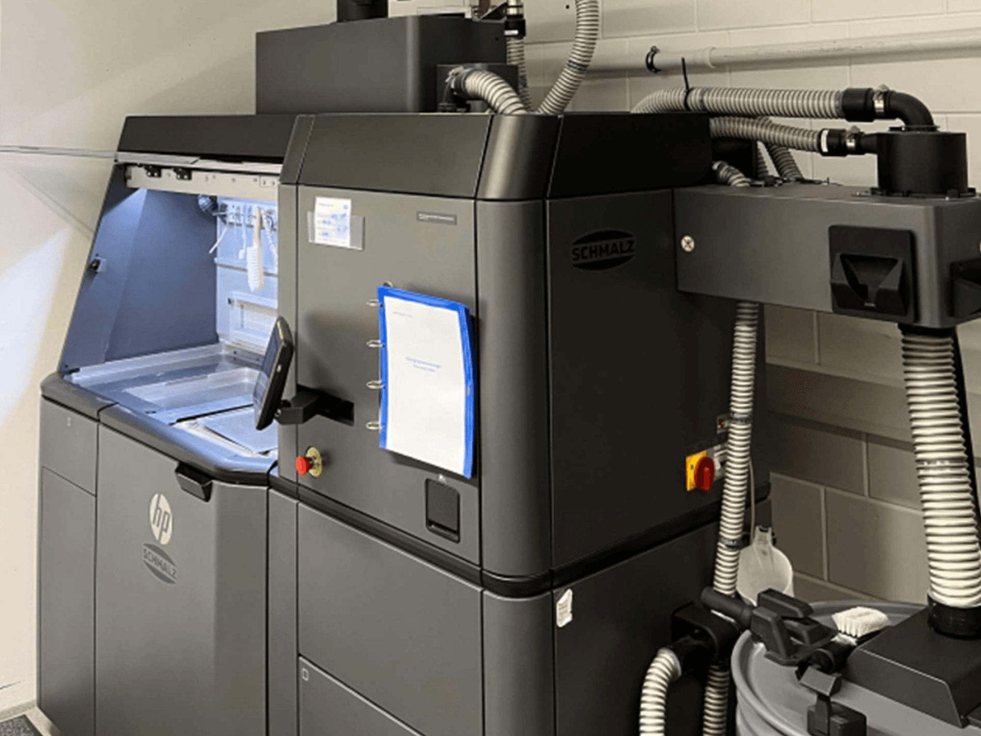 3D-принтер HP Jet Fusion 3D 4200 для печати из пластика, вид сбоку, на котором видны панель управления и внутренние компоненты.