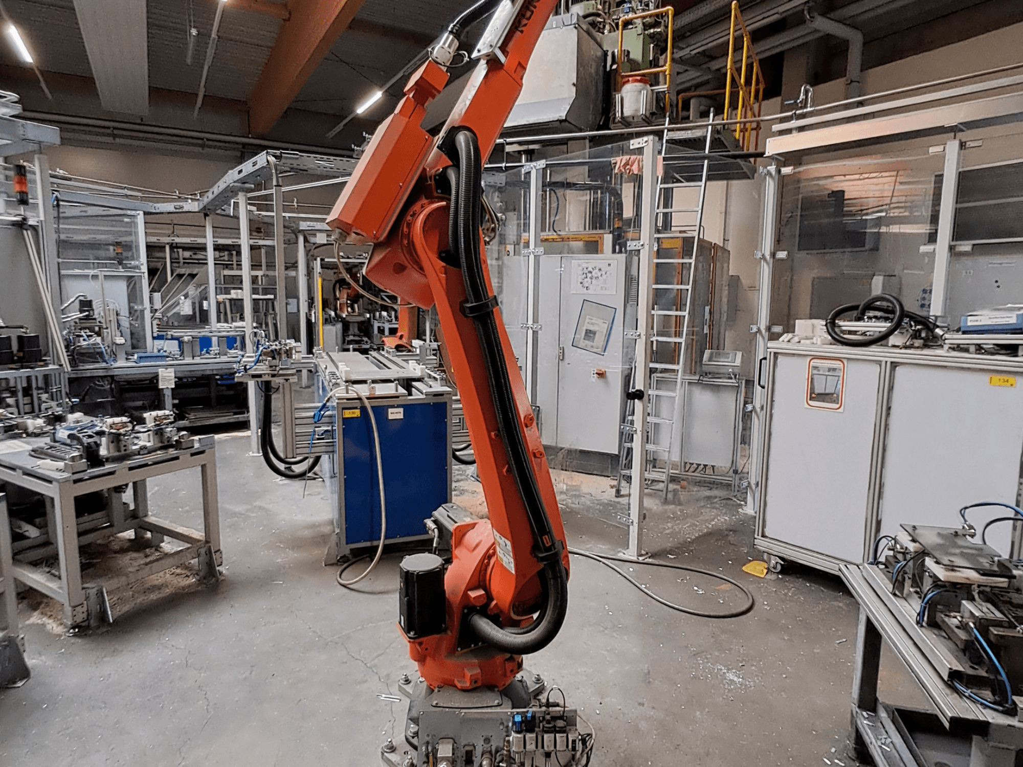 Роботизированный манипулятор KUKA KR 26 R3100/SEL в промышленной среде, вид сбоку, на заднем плане — рабочее оборудование.