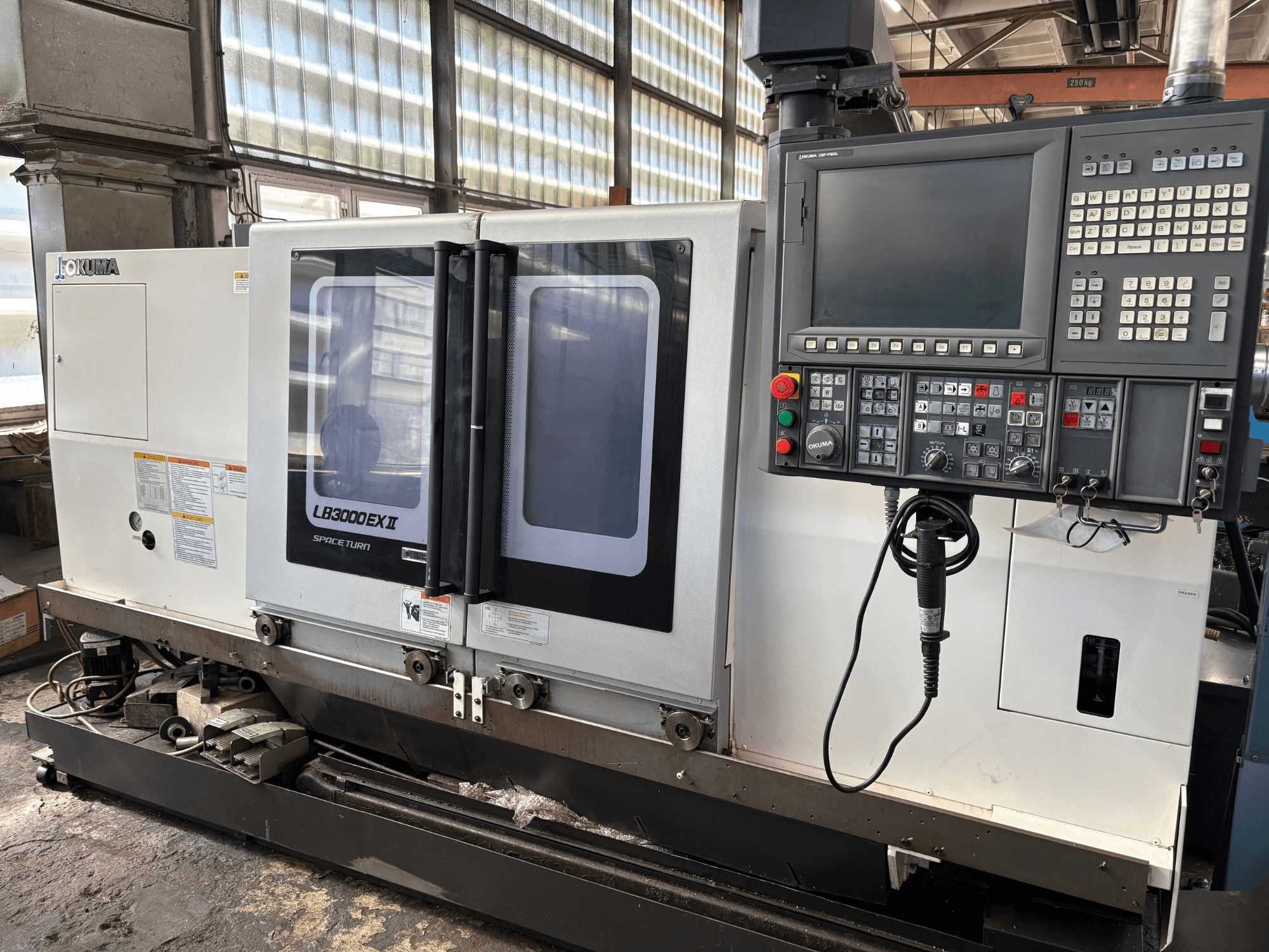 Горизонтальный токарный станок Okuma LB3000EXII, вид спереди с панелью управления и загрузочной дверцей.