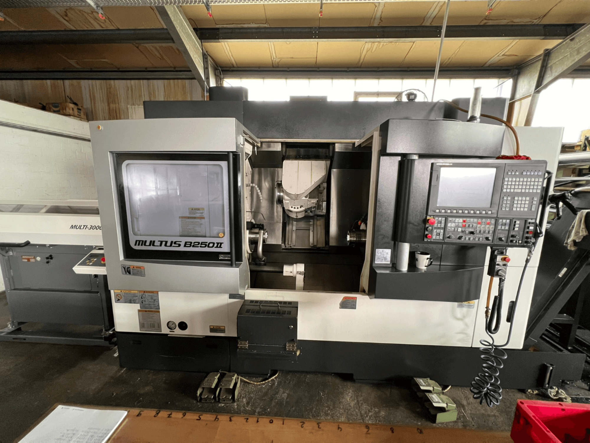 Токарно-фрезерный центр Okuma Multus B250II MW, вид спереди, с подробным изображением панели управления и зоны обработки.