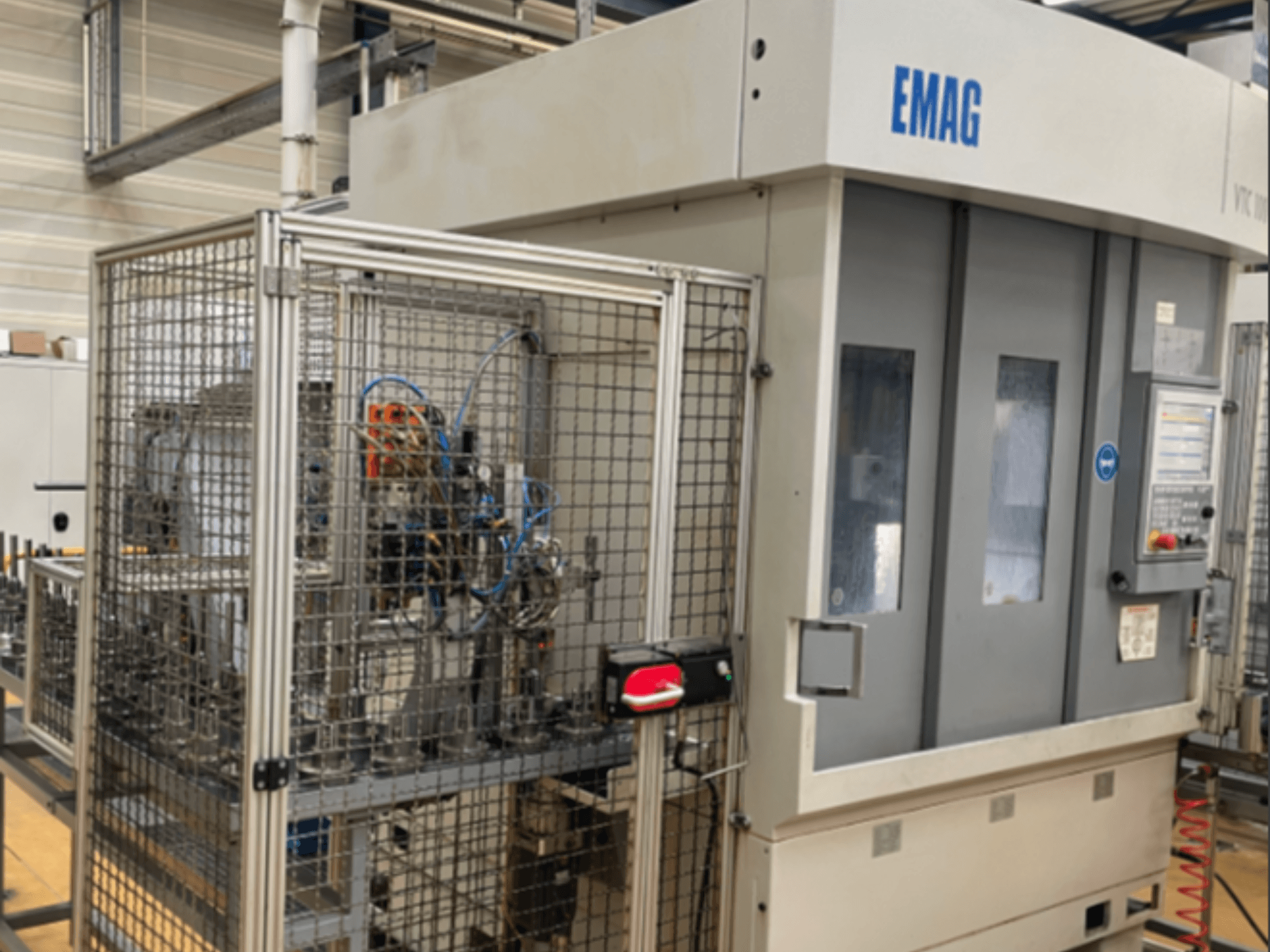 Вертикальный токарный станок EMAG VTC 100 в боковом ракурсе с подробным изображением панели управления и защитных ограждений.