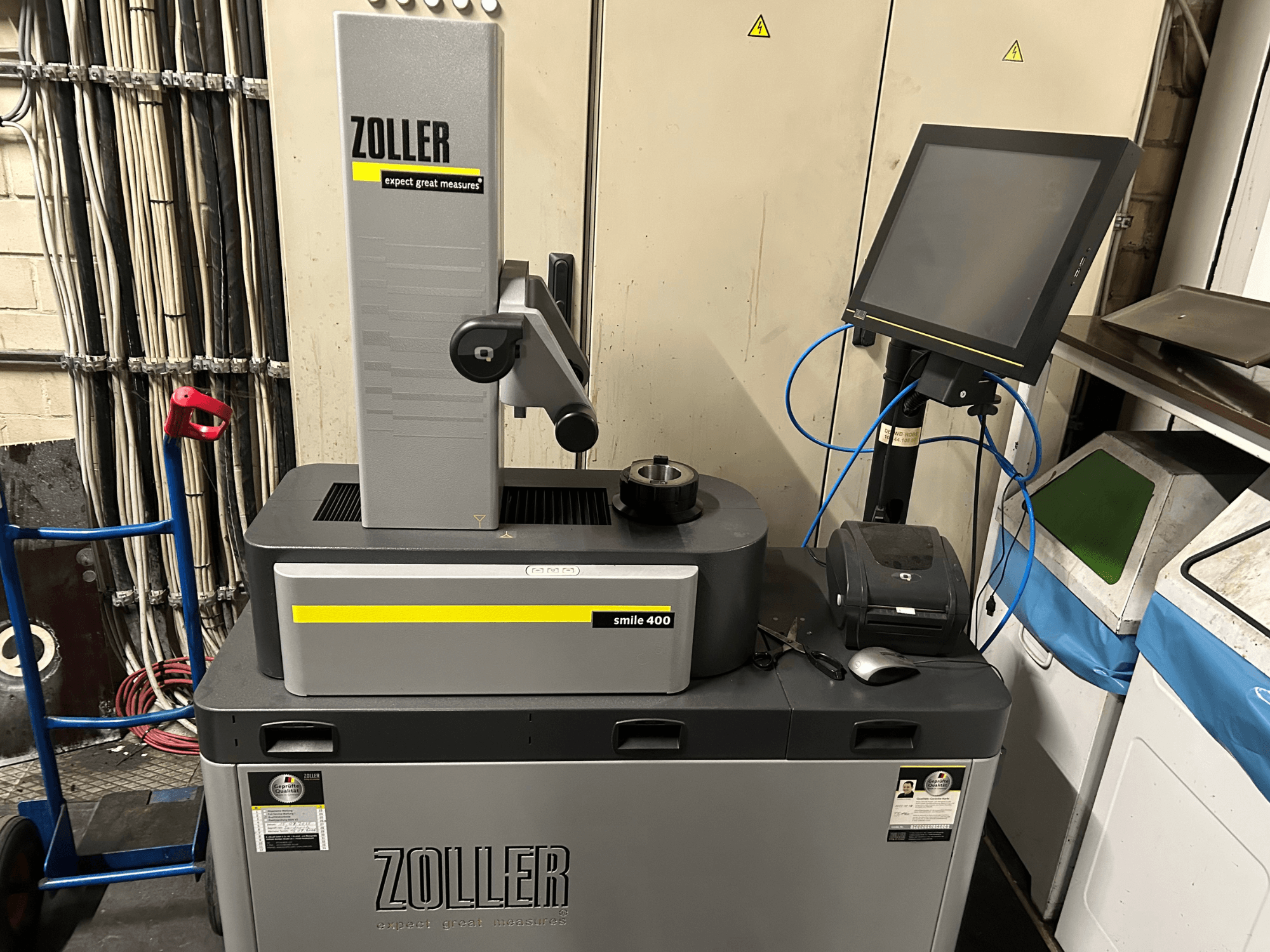 Измерительная машина ZOLLER smile 400 серого цвета, вид спереди, с сенсорным экраном, держателем инструмента и принтером на рабочей поверхности.