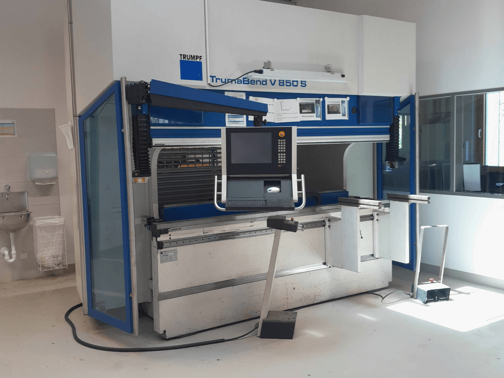 Гибочный пресс TRUMPF TrumaBend V 850 S, вид спереди с панелью управления и средствами безопасности в хорошо освещённой рабочей зоне.