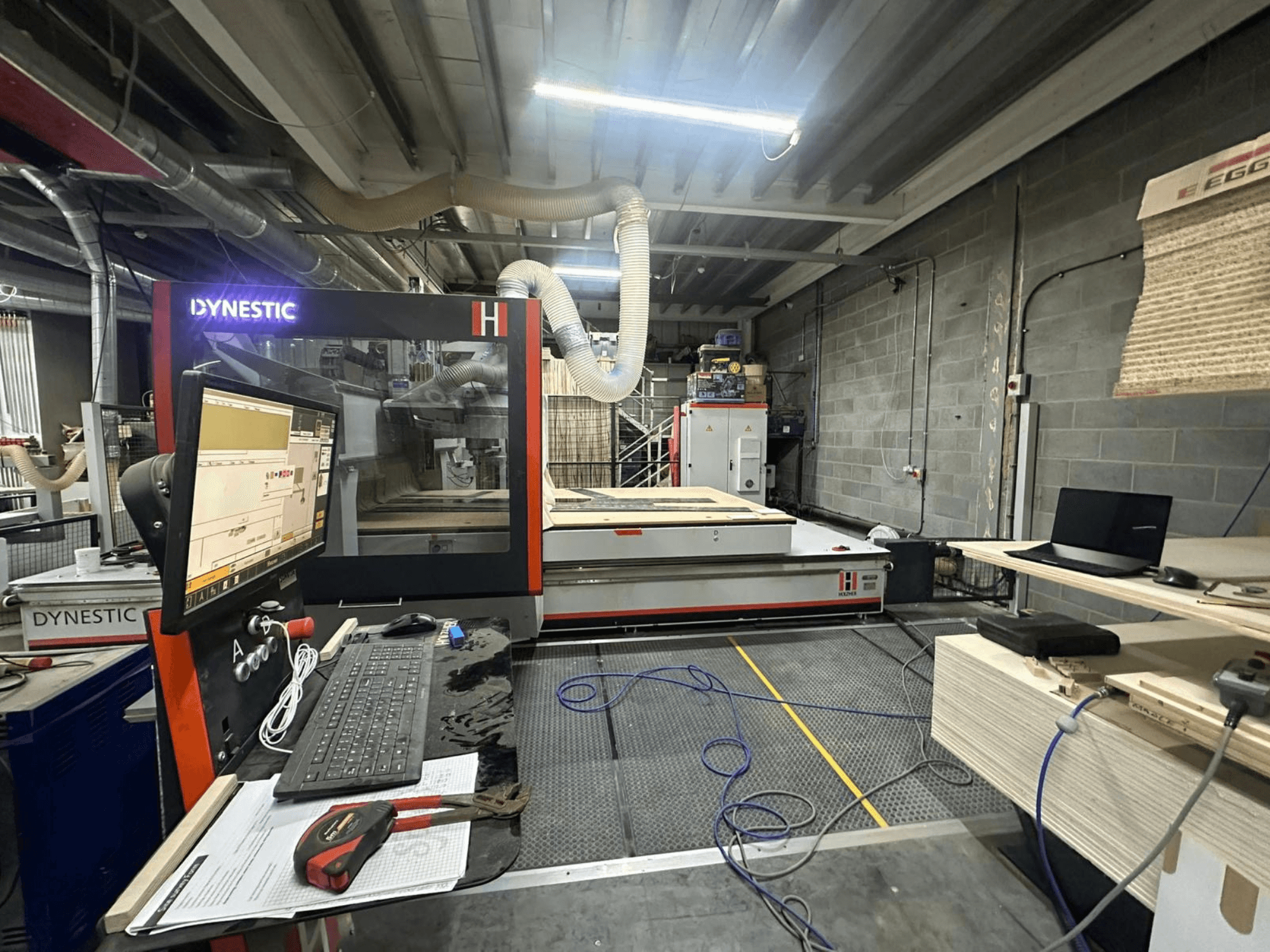 Деревообрабатывающий станок HOLZHER Dynestic 7535 в мастерской, панель управления, монитор и материалы на рабочем столе, вид спереди.