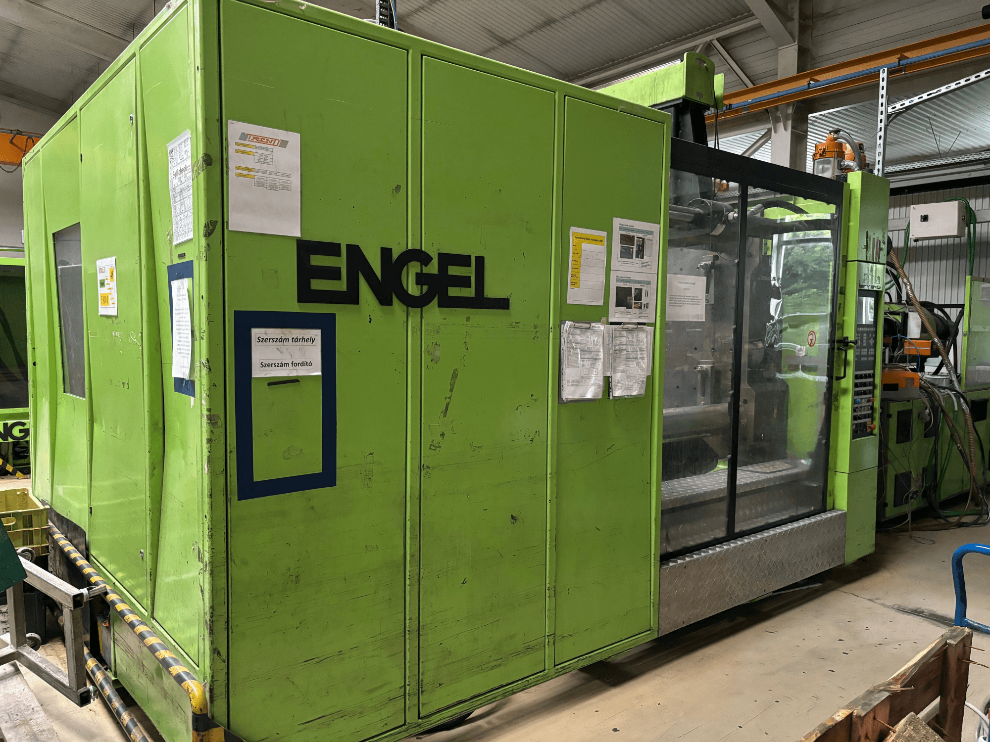 Гидравлическая машина для литья под давлением Engel DUO 5550/800, вид спереди, с зеленым внешним видом и прозрачной панелью доступа.