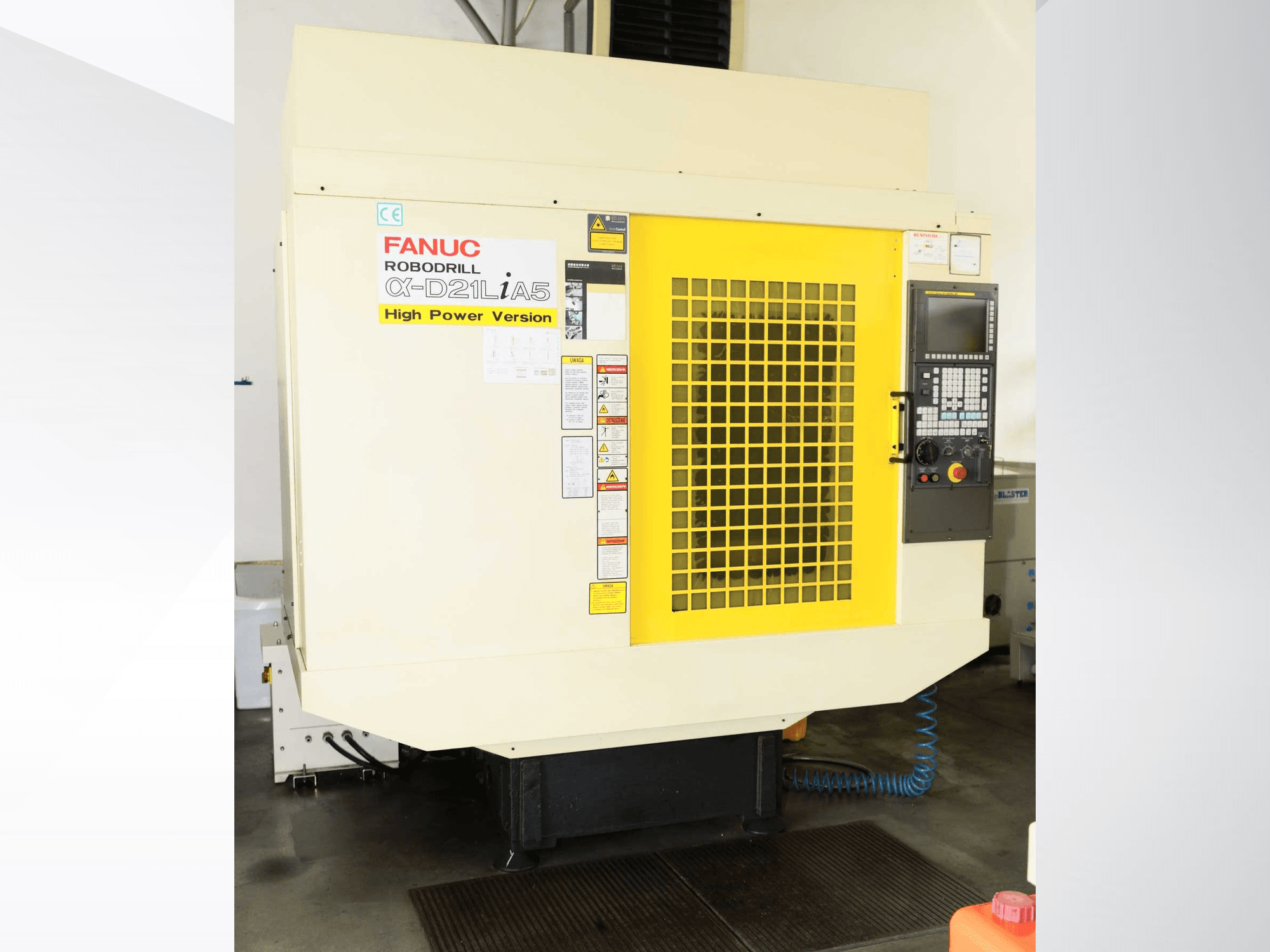 Вертикальный обрабатывающий центр FANUC ROBODRILL α-D21LiA5, вид спереди с желтой защитной решеткой и деталями панели управления.
