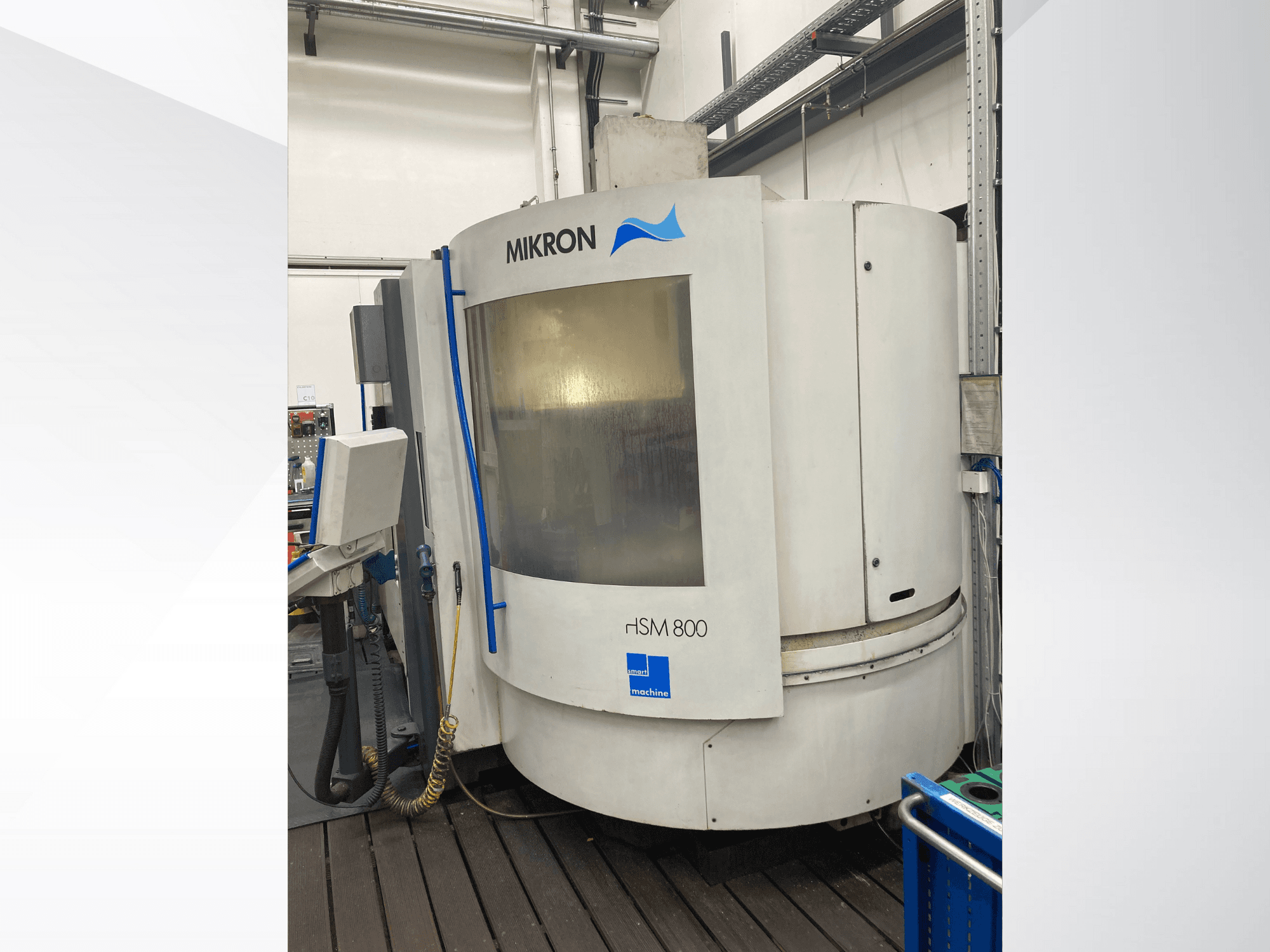Станок с ЧПУ Mikron rISM 800, вид спереди с панелью управления, цилиндрический дизайн и синие акценты, установлен в мастерской.