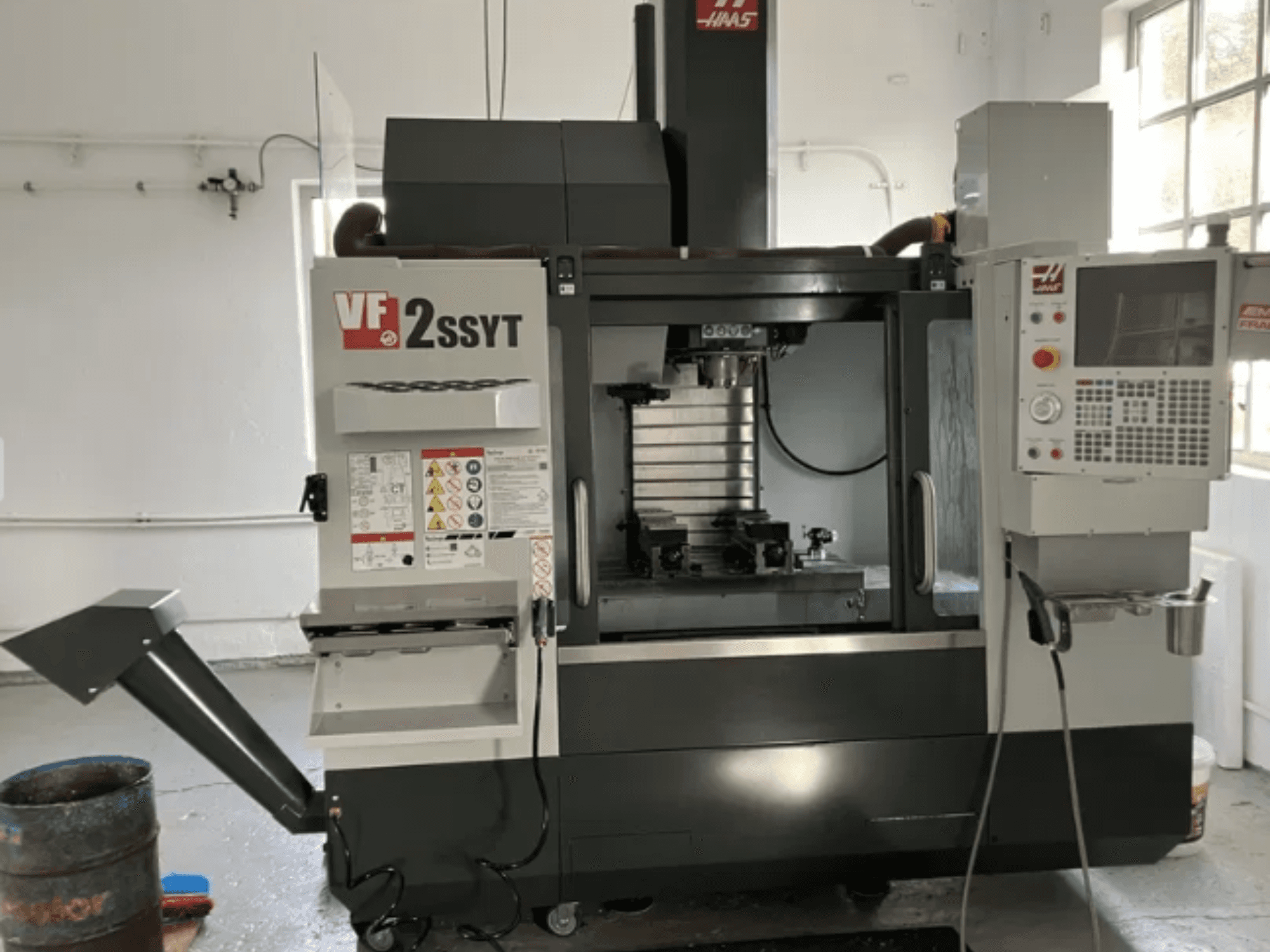 Фрезерный станок с ЧПУ Haas VF-2SSYT, вид спереди, панель управления, держатель инструмента и система подачи СОЖ для обработки металла.