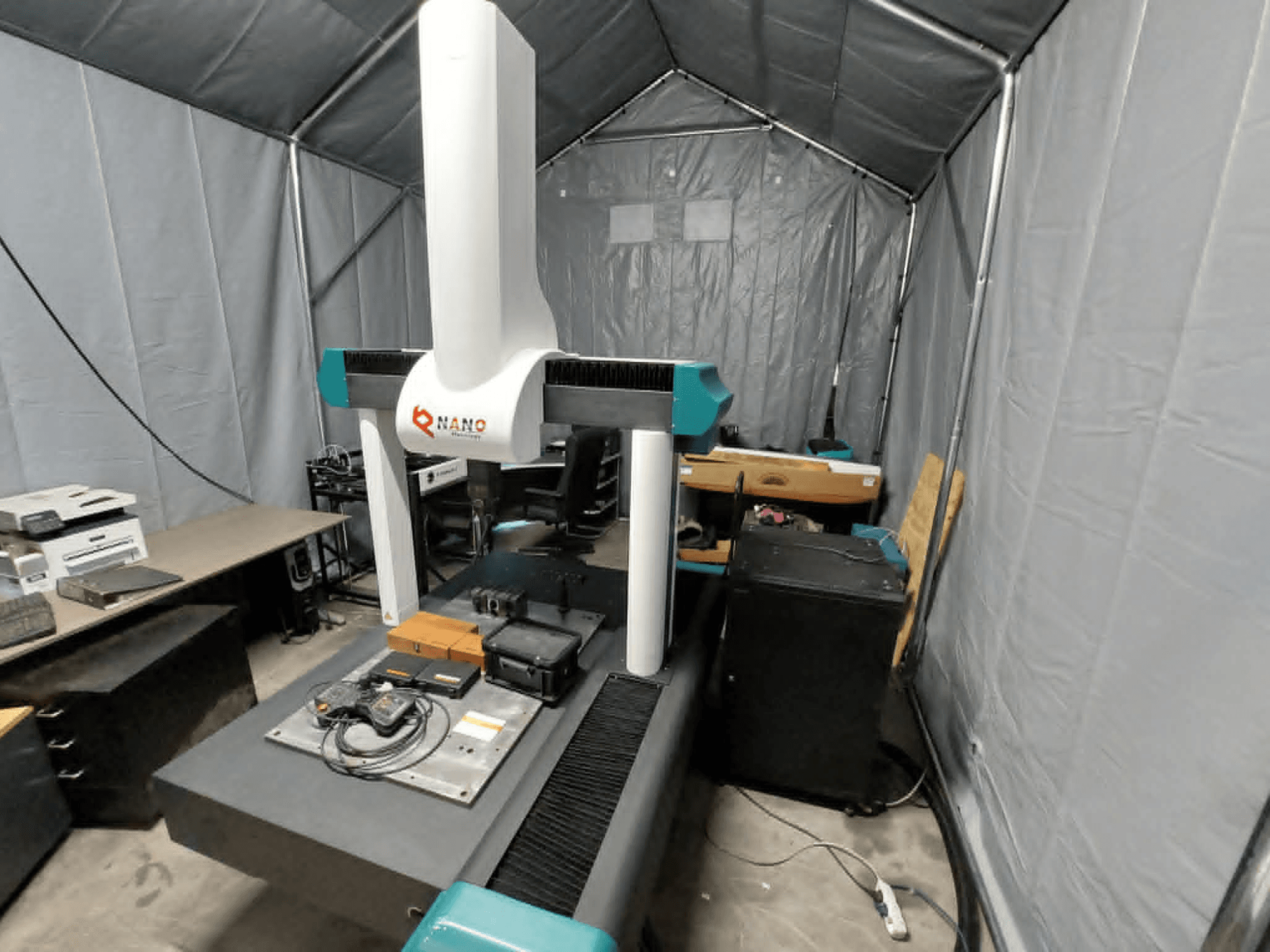NANO METROLOGY Micr 7106 CMM в палатке; вид спереди, показывающий манипулятор машины и измерительную платформу с принадлежностями.