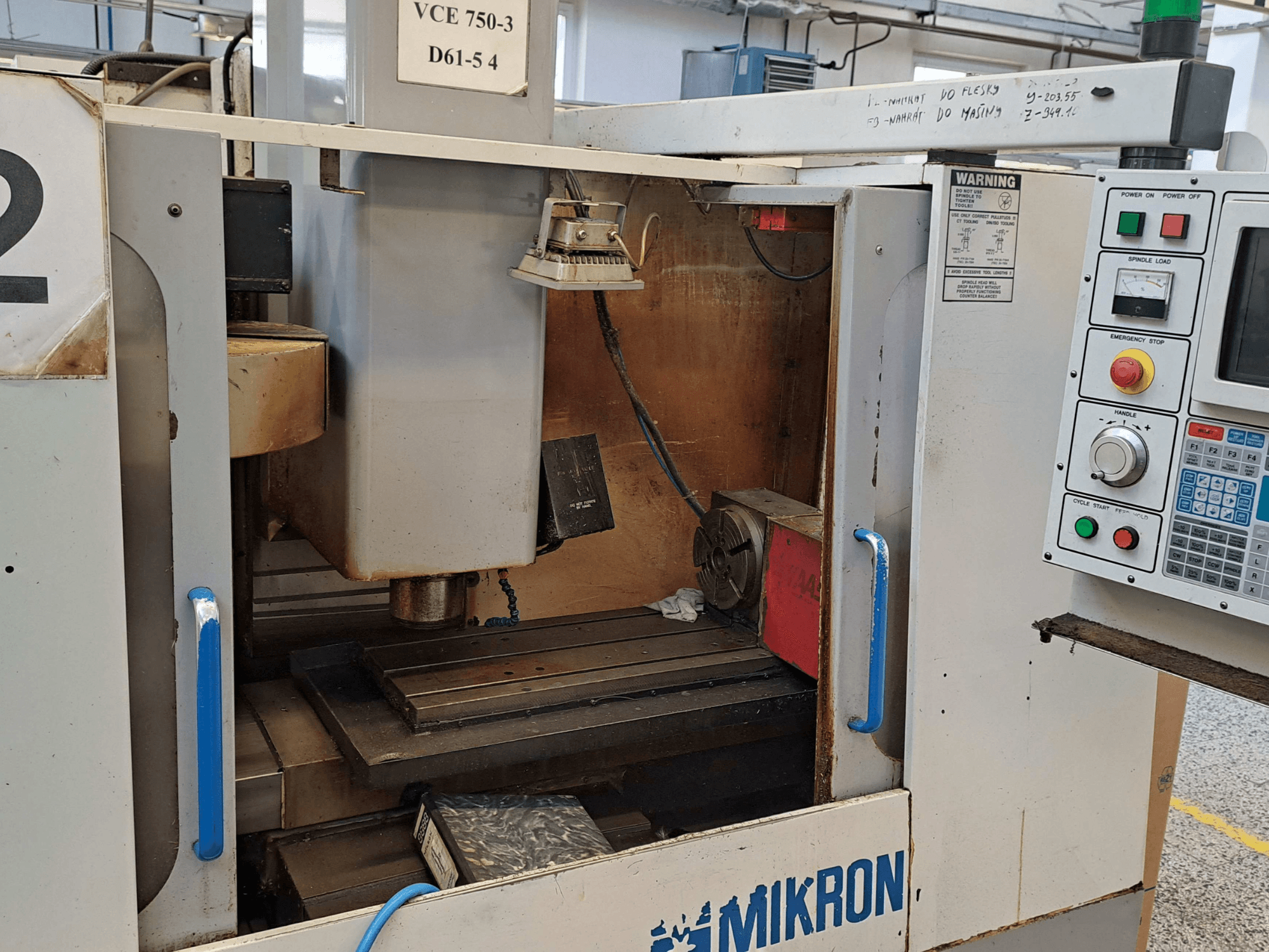 Вид спереди фрезерного станка Mikron VCE 750-3 с изображением шпинделя, панели управления и рабочего стола с техническими характеристиками.